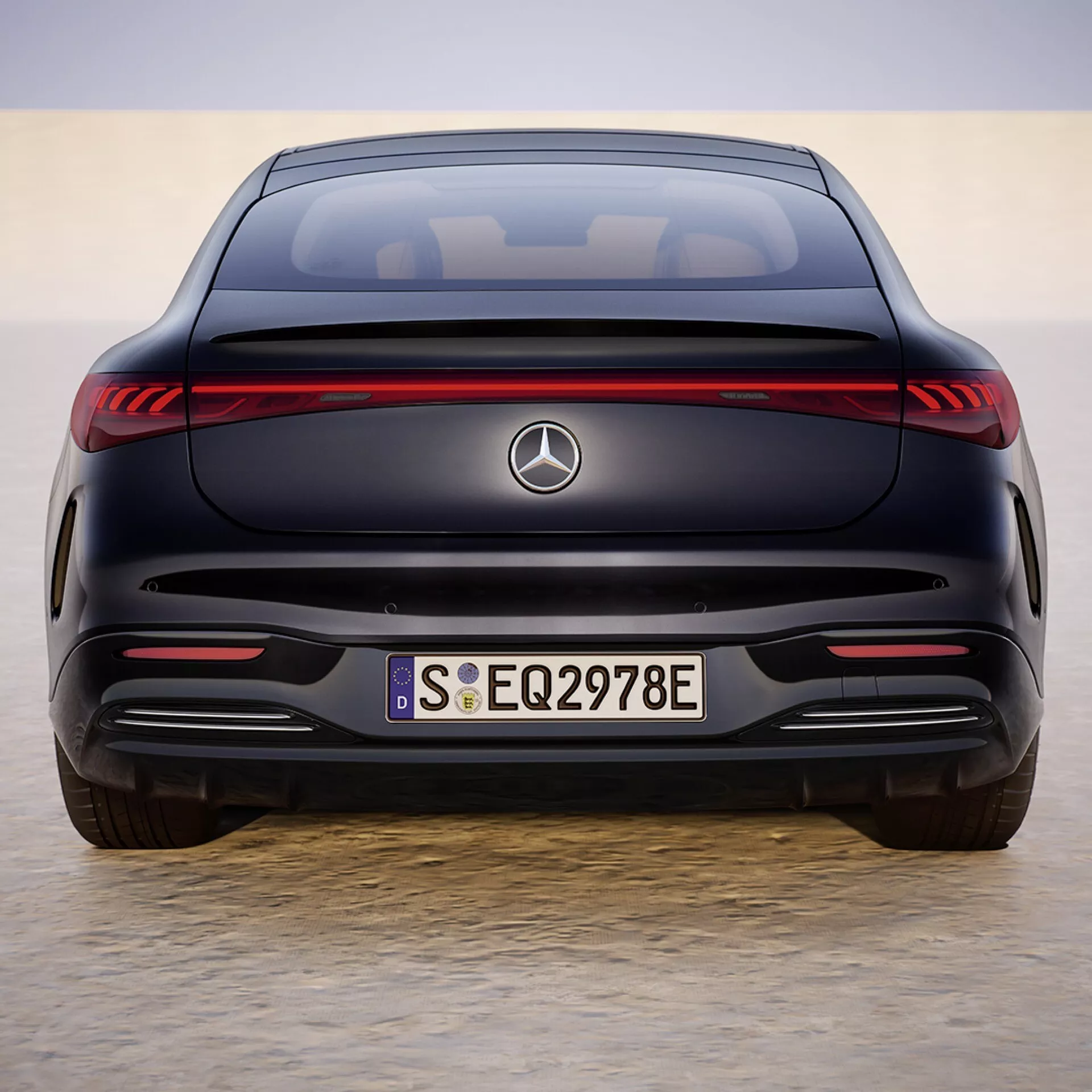 Tył Mercedes-Benz EQS 2024 z LEDowymi światłami tylnymi, emblematem, oznaczeniami EQ i 297E na bagażniku, zintegrowanym zderzakiem bez wydechów, czujnikami parkowania i sylwetką coupé wskazującą cechy luksusowego sedana elektrycznego