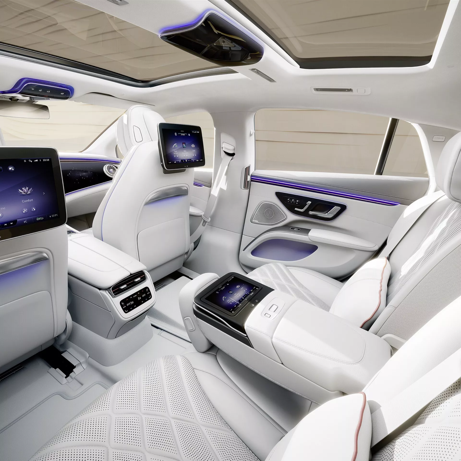 Wnętrze Mercedes-Benz EQS Facelift 2024 prezentujące luksusową kabinę tylną z widoku z lotu ptaka, z indywidualnymi konturowymi siedzeniami w pikowanej białej skórze, zintegrowaną konsolą środkową z ekranem dotykowym, dedykowanymi wyświetlaczami rozrywki dla tylnych pasażerów, zaawansowaną kontrolą klimatu, oświetleniem ambient, panoramicznym dachem i bogatymi w technologie ulepszeniami dla wyjątkowego komfortu i luksusu pasażerów.