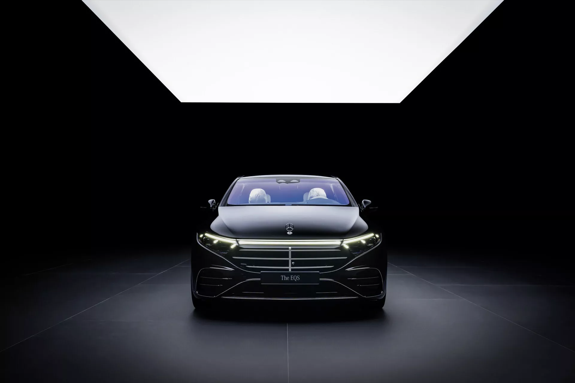Model liftingowy Mercedes-Benz EQS 2024 wyeksponowany z naciskiem na grill, reflektory i elegancki design przedni, podkreślony przez miękkie oświetlenie z góry na ciemnym tle, uchwycenie esencji luksusu i nowoczesnego rzemiosła samochodowego.