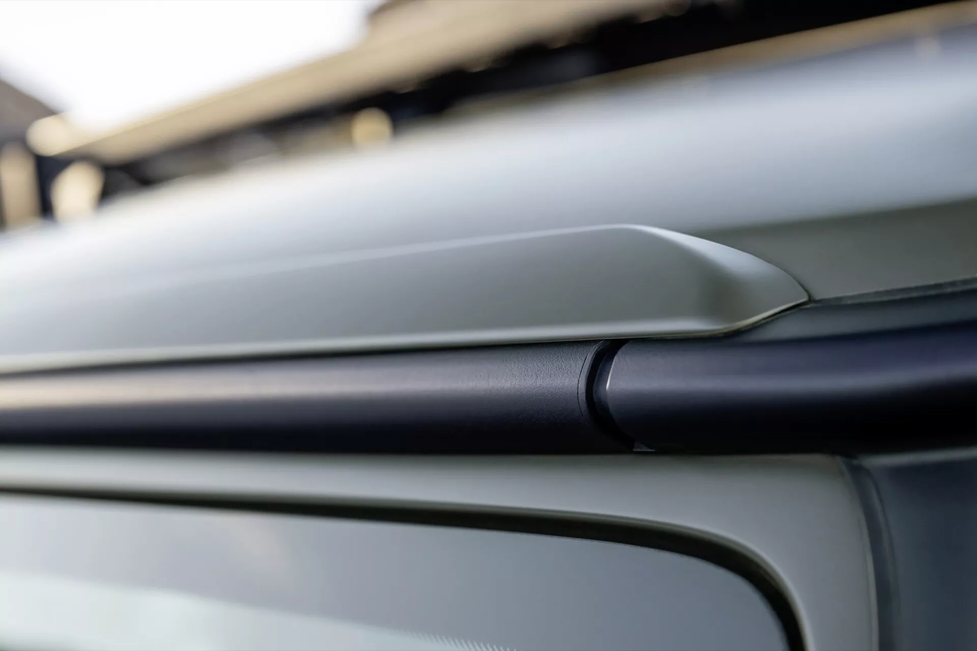 Szczegół projektu zewnętrznego Mercedes-Benz Klasy G 2024 podkreślający konturową linię i gładką metaliczną karoserię z ukosa