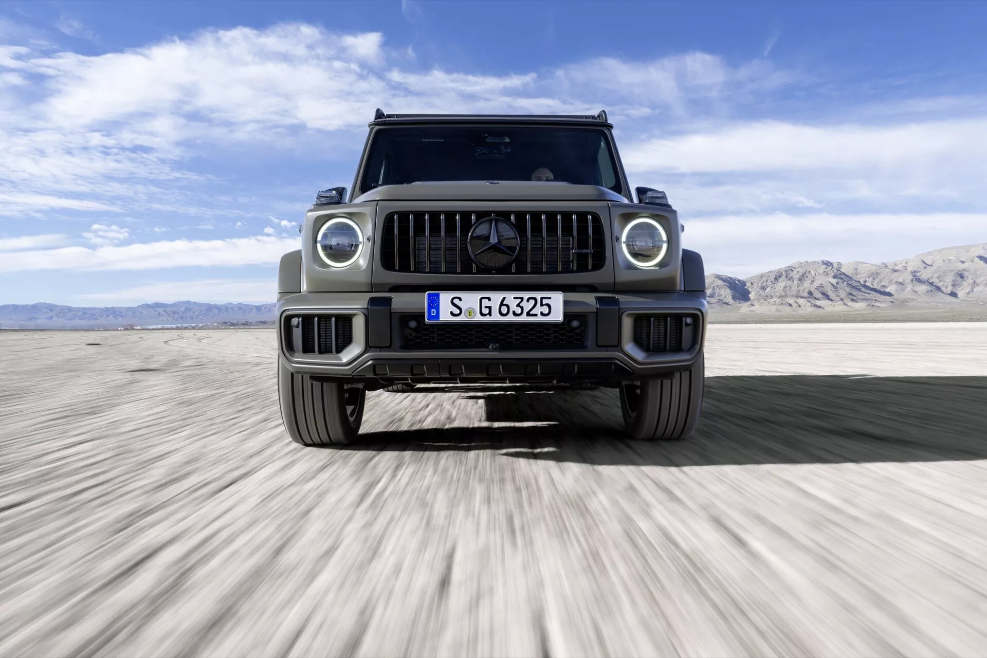 Luksusowy SUV Mercedes-Benz Klasy G (G 465) na rok 2024, widok z przodu na pustyni, z reflektorami LED, charakterystyczną atrapą z emblematem i zdolnościami terenowymi.