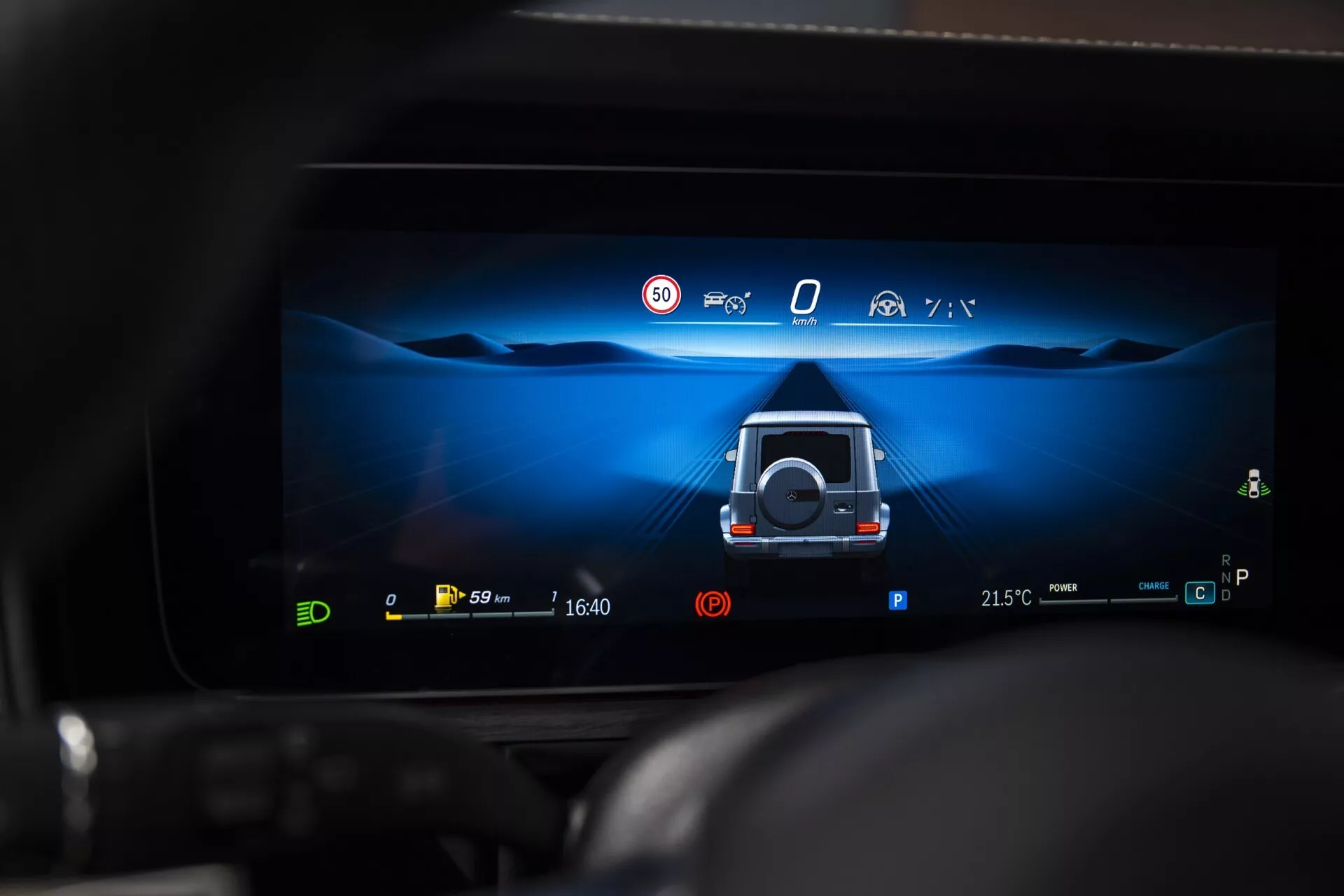 Wyświetlacz cyfrowego deski rozdzielczej Mercedes-Benz G-Klasse 2024 pokazujący widok pomocy przy parkowaniu 360 stopni z aktywnymi funkcjami bezpieczeństwa i wskaźnikami napędu elektrycznego
