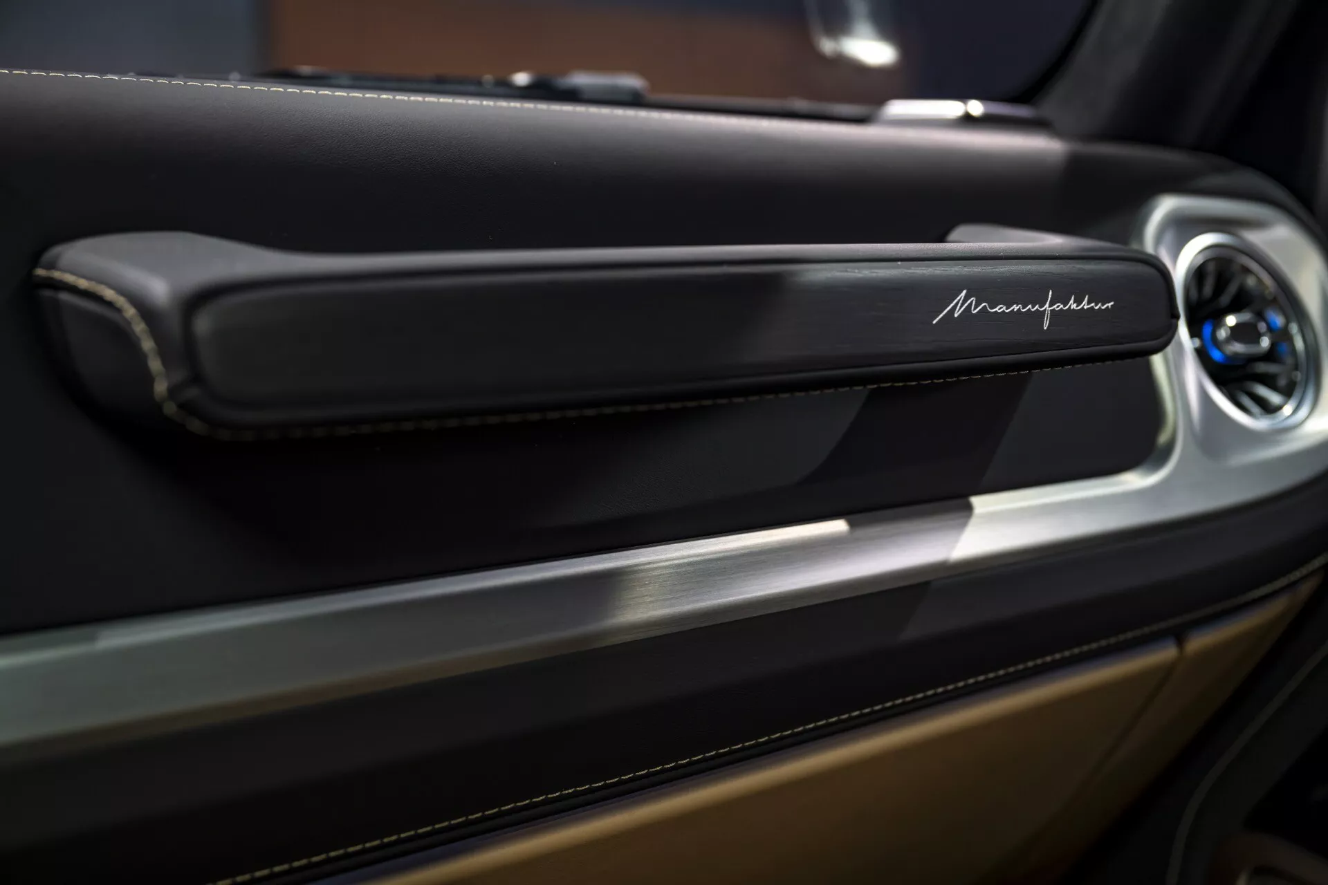 Zbliżenie na panel drzwi Maserati skupiające się na eleganckiej, nowoczesnej klamce z metalicznym wykończeniem i potencjalnym przyciskiem sterującym, podkreślające luksusowe detale wnętrza.
