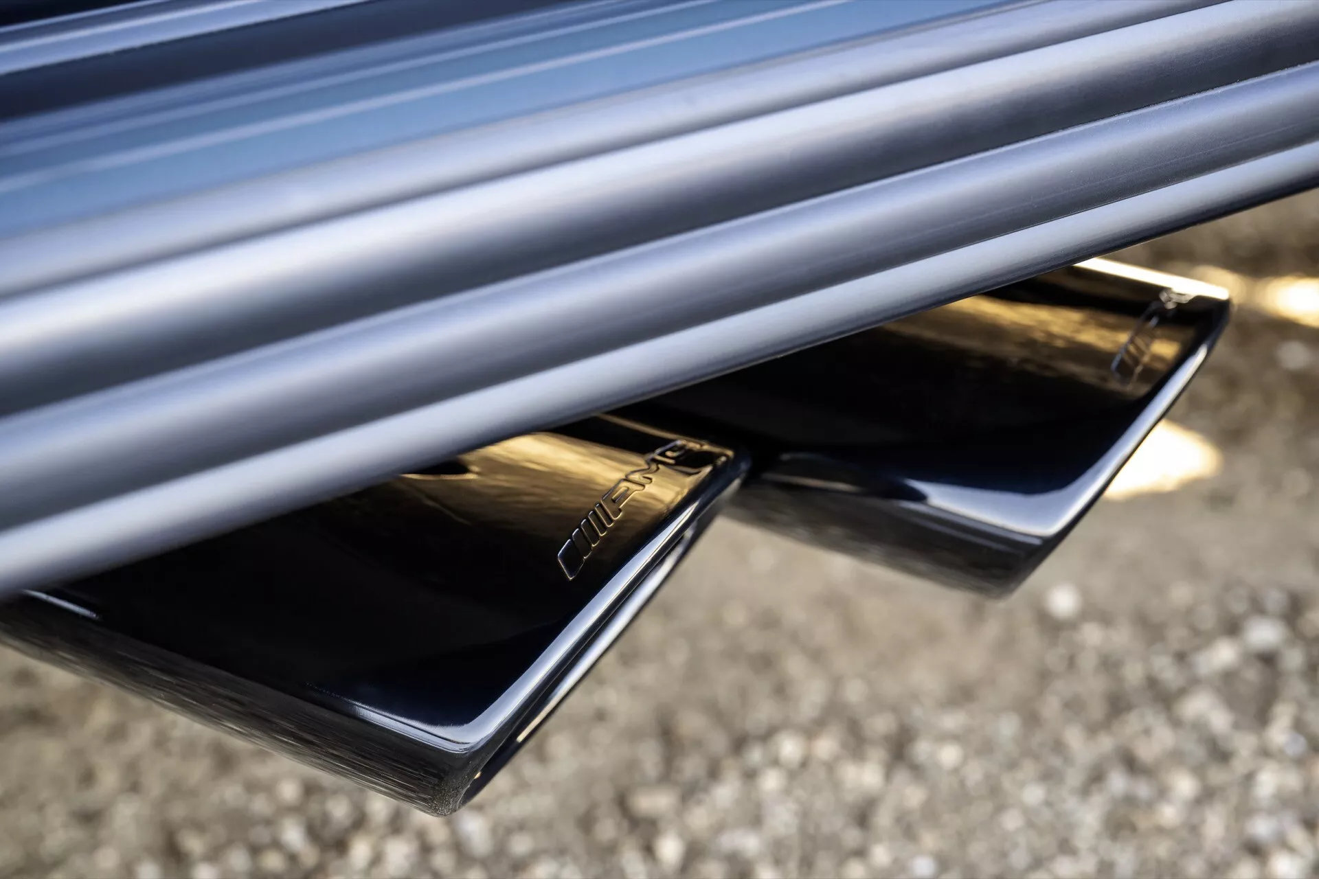 Zbliżenie na podwójne końcówki wydechu Mercedes-Benz klasy G (G 465) rocznik 2024 z wykończeniem chromowanym, zintegrowane z tylnym zderzakiem dla eleganckiego wyglądu, podkreślające wydajność i jakość estetyczną pojazdu.