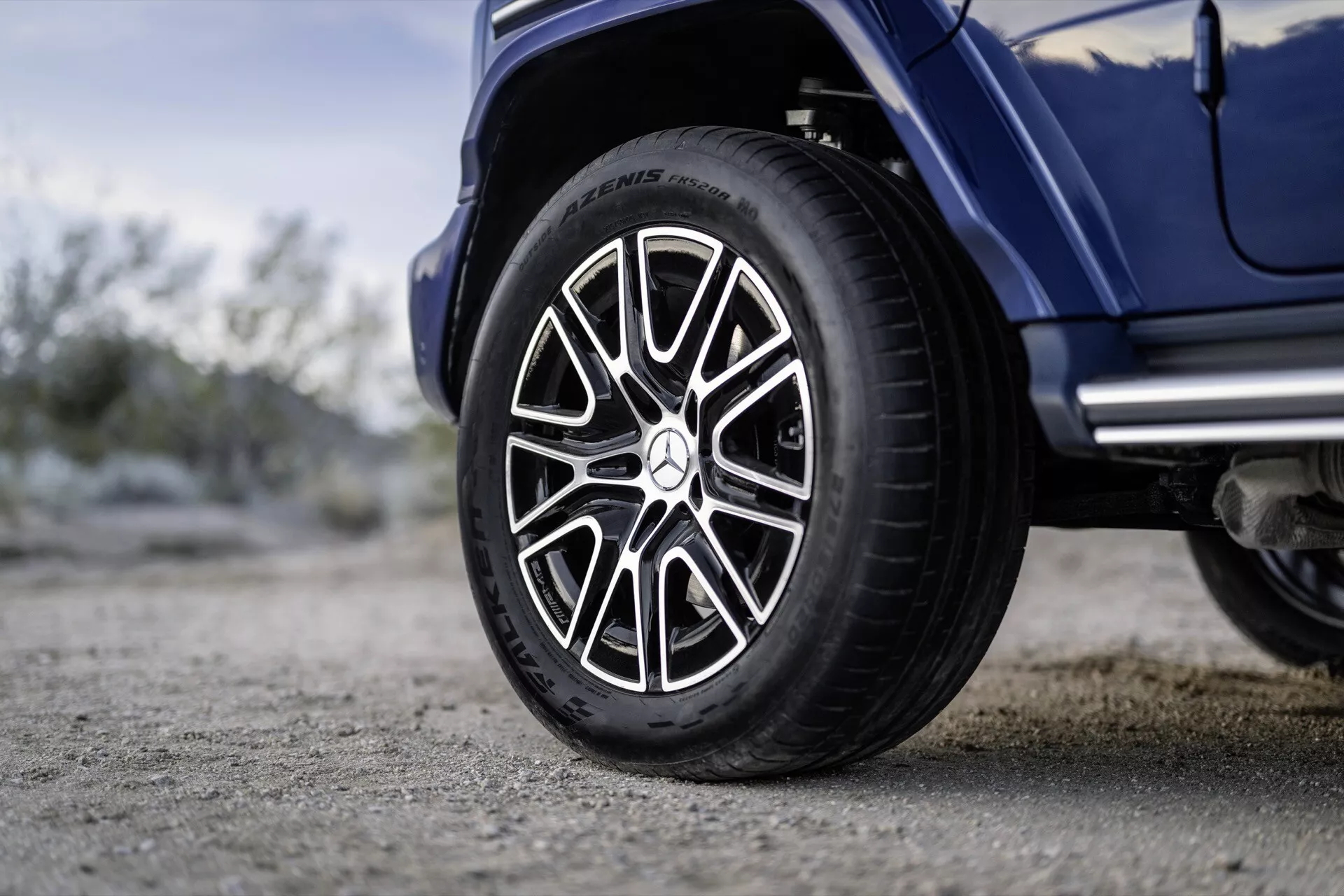 Zbliżenie na prawe koło Mercedes-Benz G-Klasse 2024 z oponą Michelin i złożonym sportowym wzorem felgi, na zewnątrz