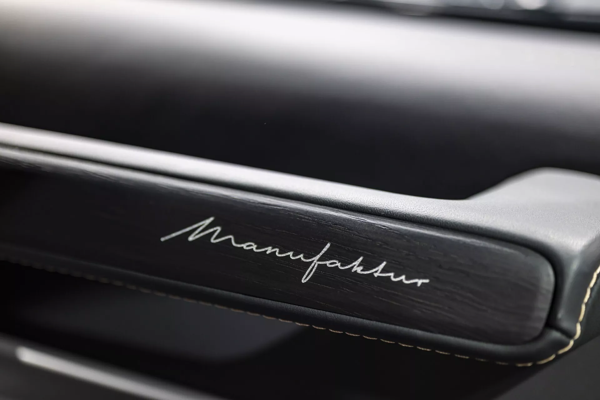 Zbliżenie wnętrza Mercedes-Benz G-Klasse 2024 pokazujące szczegółowe szwy i napis 'Manufaktur' na skórze, podkreślające luksusową personalizację