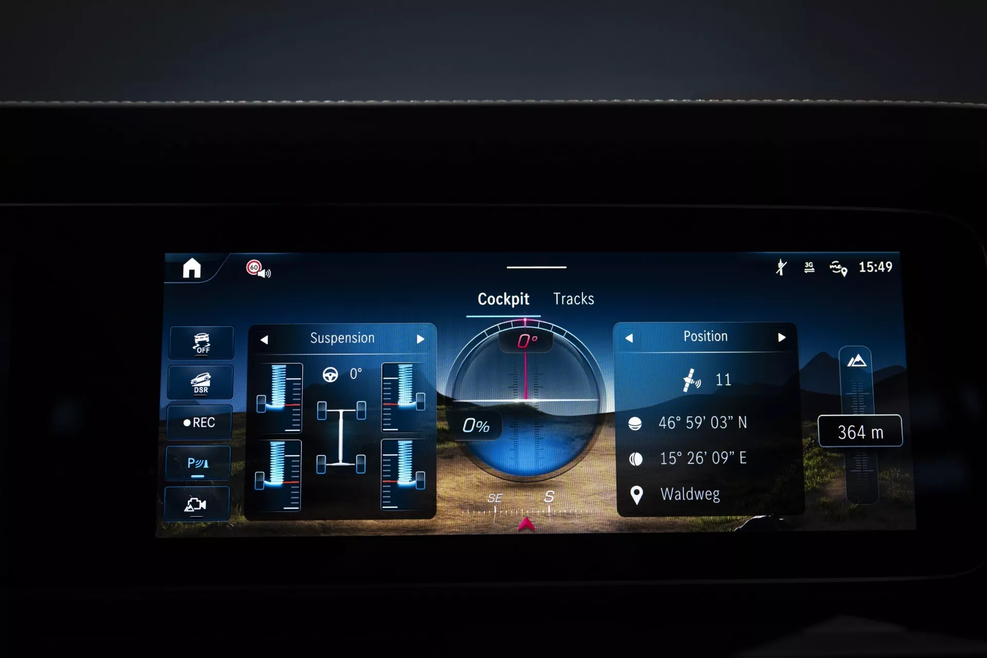 Ekran systemu infotainment Mercedes-Benz G-Klasse 2024 pokazujący ustawienia zawieszenia, współrzędne GPS, dostosowywalne informacje o kokpicie oraz funkcję ścieżek jazdy, skupiając się na zaawansowanej technologii pojazdu