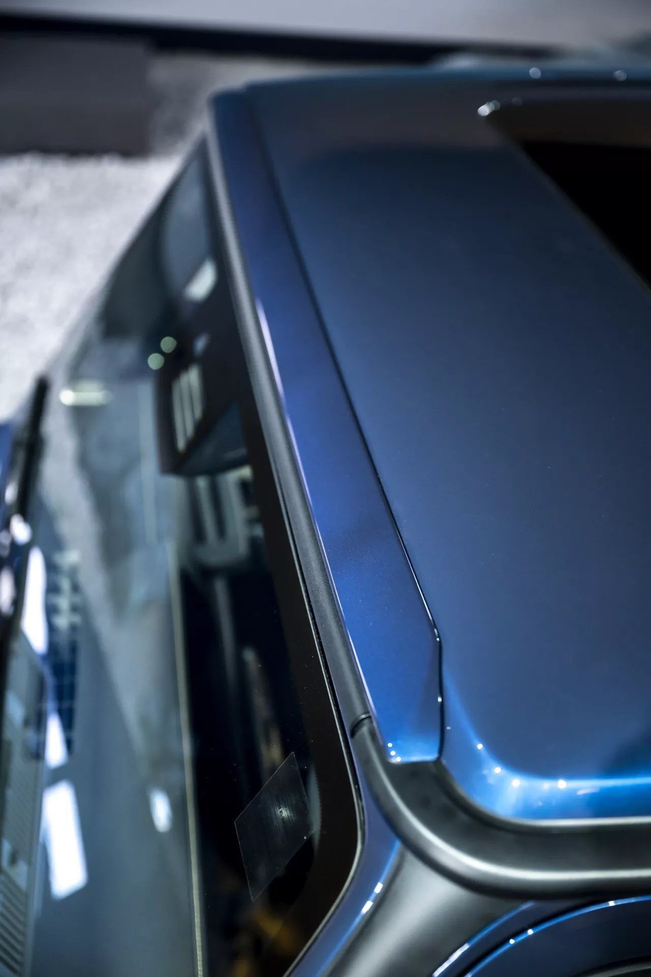 Zbliżenie na maskę i górną część błotnika Mercedes-Benz G-Klasse 2024 (465), prezentujące jej krzywiznę, detale konstrukcyjne i premium metaliczne wykończenie z podniesionego kąta.