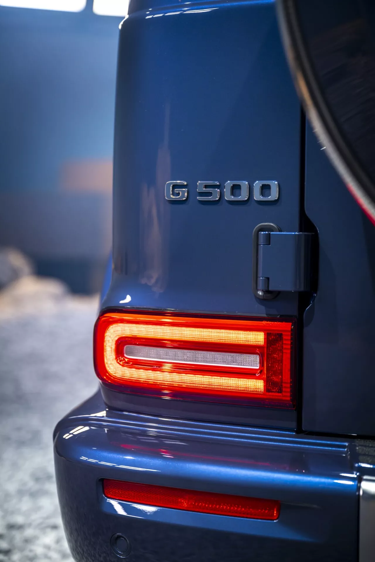 Tylna część Mercedesa-Benz klasy G (G 500) na rok 2024 z nowoczesnymi czerwonymi światłami LED, podkreślająca wysokiej jakości, solidną konstrukcję oraz status symbolu luksusowego SUV-a z wyraźnym widokiem na uchwyt koła zapasowego i oznaczenie modelu.