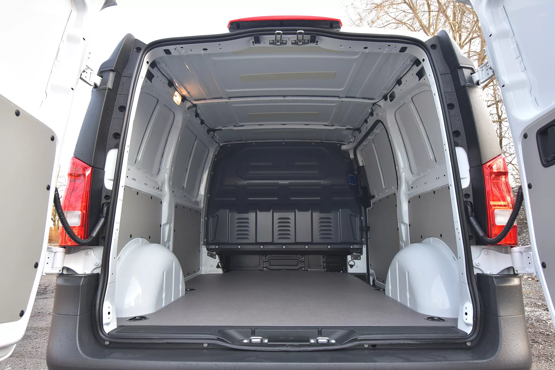 Tylny widok wnętrza Mercedes-Benz Vito Tourer z 2014 roku prezentujący przestronny i pusty przestrzeń ładunkową z otwartymi drzwiami, panelami ochronnymi i punktami mocowania ładunku