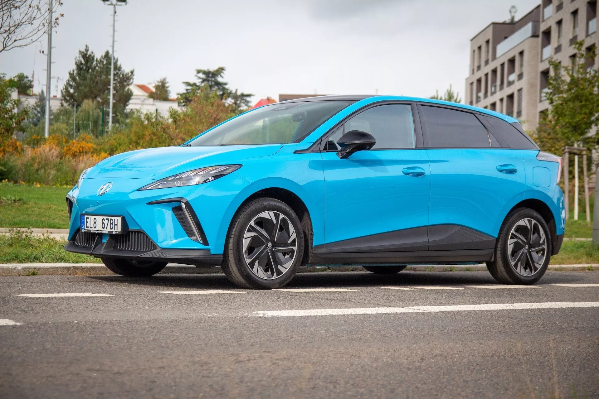 Elektryczny hatchback MG MG4 2022 w jasnym niebieskim kolorze, pokazujący sportową postawę, aerodynamiczny profil i przednie lewe reflektory LED z niskiego kąta bocznego