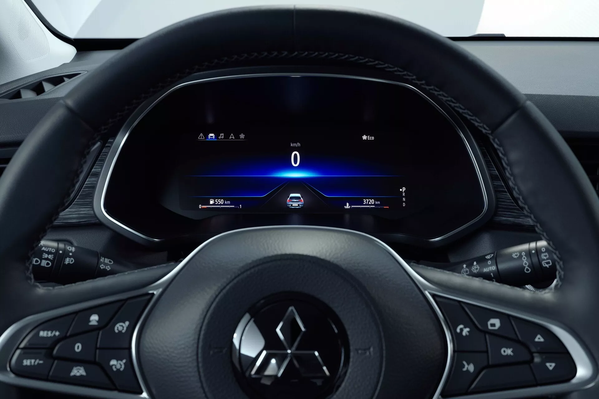 Wnętrze Mitsubishi ASX 2023 (2. generacja) z perspektywy kierowcy, skupiające się na trójramiennej wielofunkcyjnej kierownicy z przyciskami do sterowania mediami, telefonu, tempomatu oraz z emblematem producenta. Za nią w pełni cyfrowy zestaw wskaźników pokazujący prędkościomierz na 0 km/h, kierunkowskazy, czas i licznik kilometrów. Kokpitowy układ wskazuje na projekt skoncentrowany na kierowcy z elegancką i nowoczesną estetyką, podkreślającą technologię i łatwy dostęp do informacji i kontroli pojazdu.