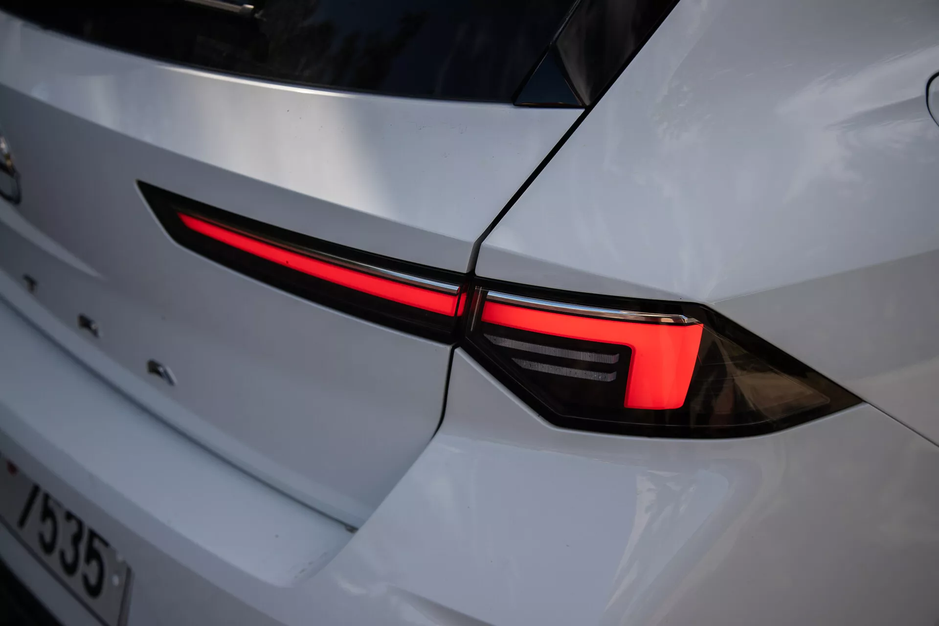Zbliżenie na lewe tylne światło Opel Astra 2022, prezentujące elegancki design LED i integrację z białą karoserią o sportowym wyglądzie