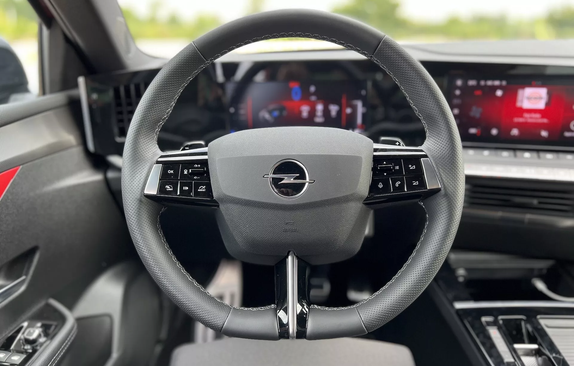 Wnętrze Opel Astra 2022 z perspektywy siedzenia kierowcy skupiające się na nowoczesnej wielofunkcyjnej kierownicy i cyfrowym panelu przyrządów