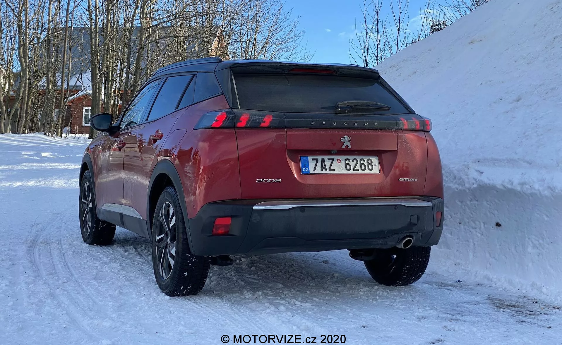 SUV Peugeot 2008 1.2 PureTech 100 Active 2020 w zimowej scenerii, widok z trzech czwartych tylnego widoku z podkreśleniem klapy bagażnika, tylnych świateł LED w kształcie szponów, czujników parkowania na tylnym zderzaku, podwójnego wydechu, europejskiej rejestracji i wieloszprychowych felg z oponami zimowymi.