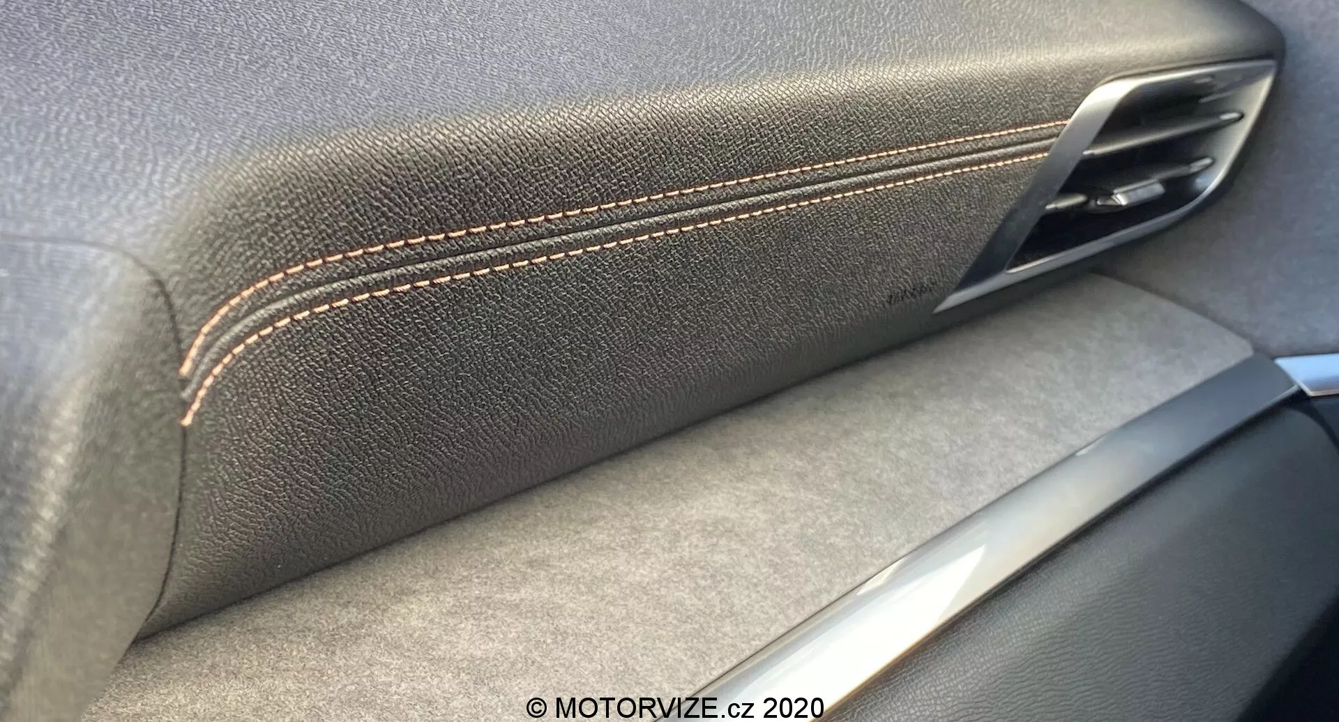Zbliżenie wnętrza panelu drzwi Peugeot 3008 2021, ukazujące zbieżność skórzanego podłokietnika z kontrastującymi szwami i metalicznej klamki drzwi. Srebrne akcenty sugerują skupienie na rzemiośle i jakości materiałów, z cieniami wskazującymi na źródło światła wewnątrz.