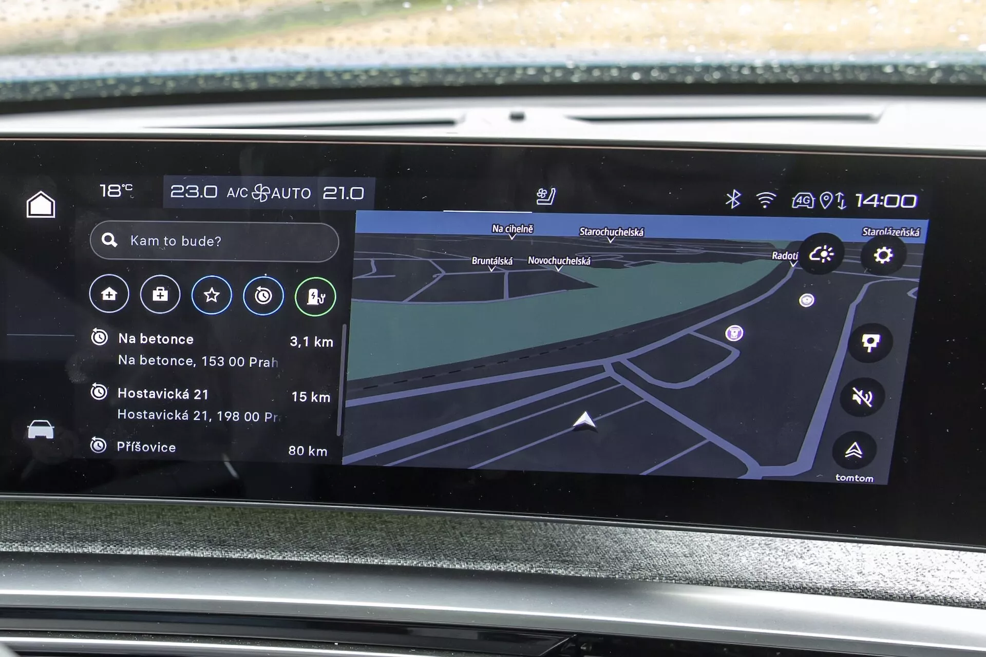 Zbliżenie na system infotainment samochodu Peugeot 3008 2024 (e-3008) z lekko pochylonej perspektywy z przodu, pokazujący ekran dotykowy z mapą nawigacyjną, ikony multimedialne, ustawienia klimatyzacji (18°C, AUTO) i zegar 14:00, zintegrowany w miękkiej desce rozdzielczej z kratkami wentylacyjnymi.