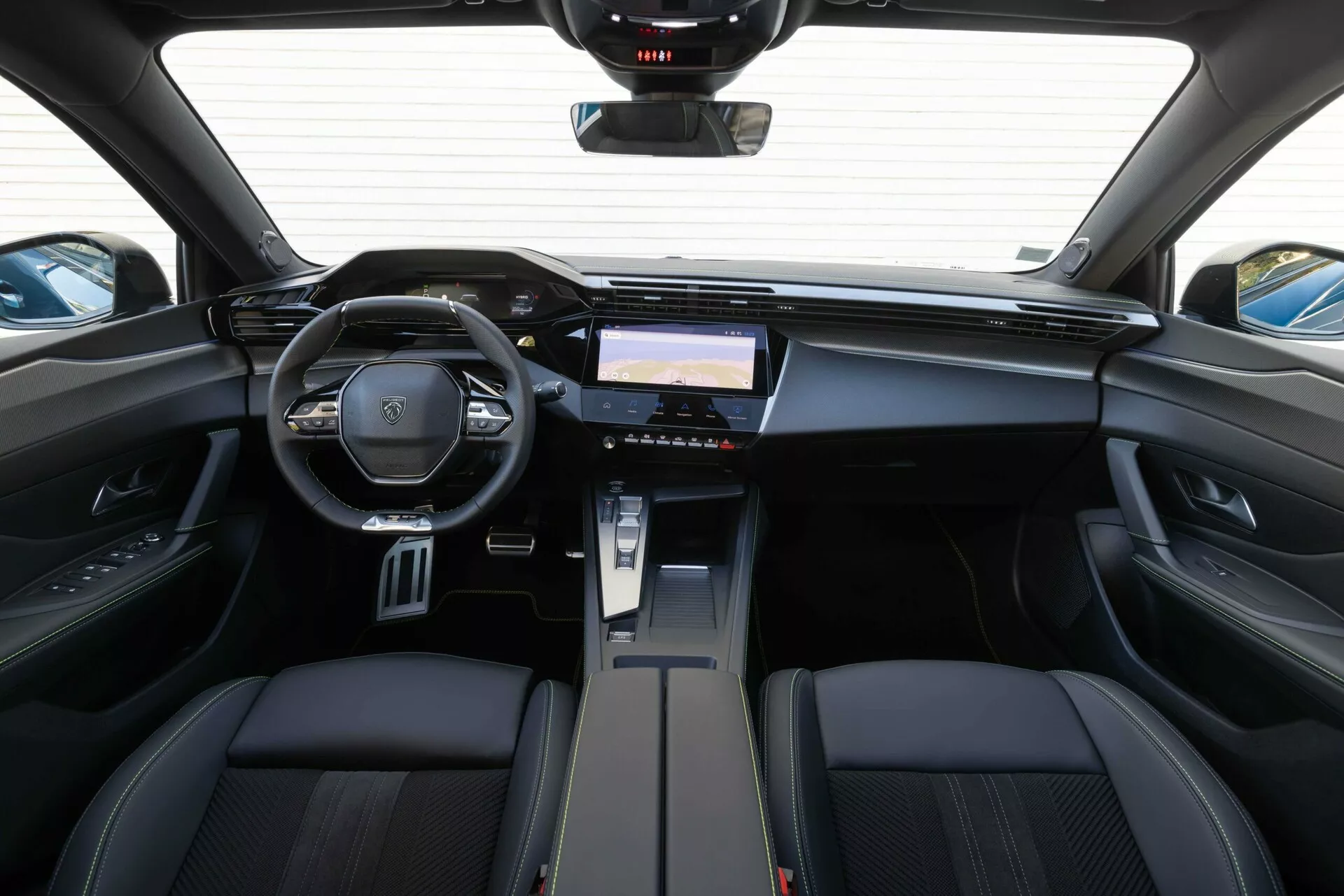 Widok wnętrza Peugeot 408 2023 z tylnej części kabiny, podkreślający deskę rozdzielczą, wielofunkcyjną kierownicę z emblematem marki i zaawansowany system infotainment