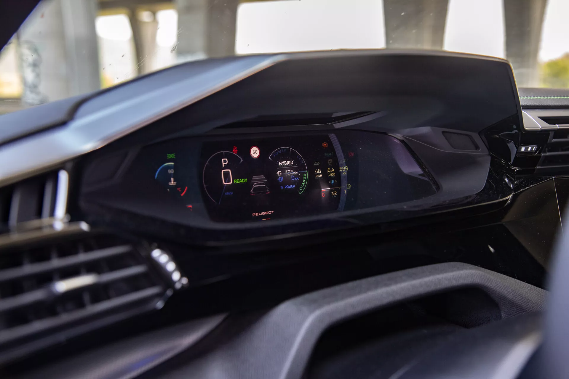 Wnętrze Peugeot 408 2023 ukazujące nowoczesną cyfrową deskę rozdzielczą z perspektywy siedzenia kierowcy, podkreślającą cyfrowy panel wskaźników z pojazdem w trybie parkowania i wysokim poziomem naładowania baterii