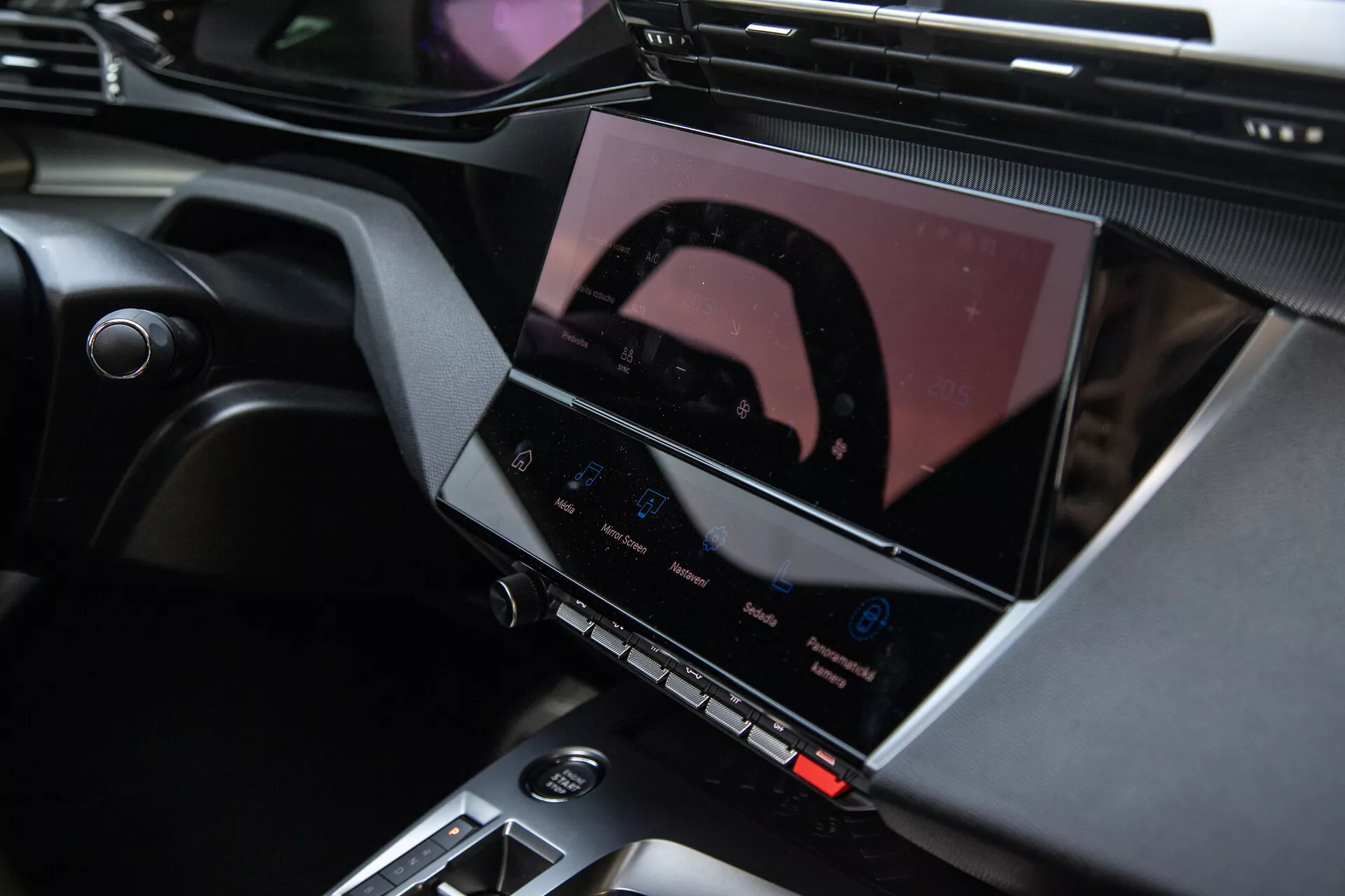 Wnętrze Peugeot 408 2023 pokazujące konsolę środkową i zaawansowany system infotainment z ekranem dotykowym, przyciskami kontroli klimatu i eleganckimi akcentami projektowymi