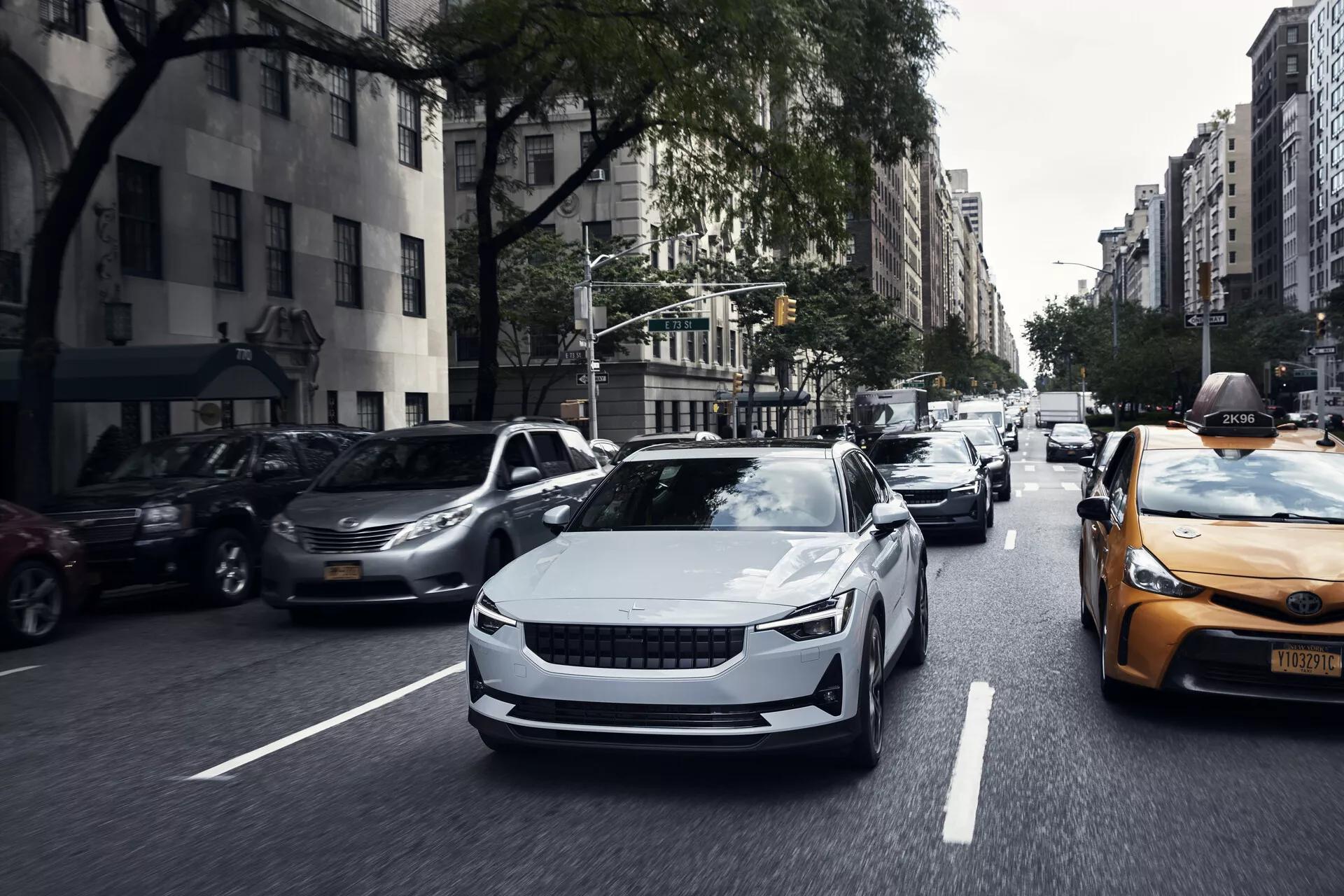 Widok z przodu elektrycznego samochodu Polestar 2 pierwszej generacji z 2020 roku w ruchu, prezentujący jego elegancki design, aerodynamiczne linie i nowoczesne reflektory LED.