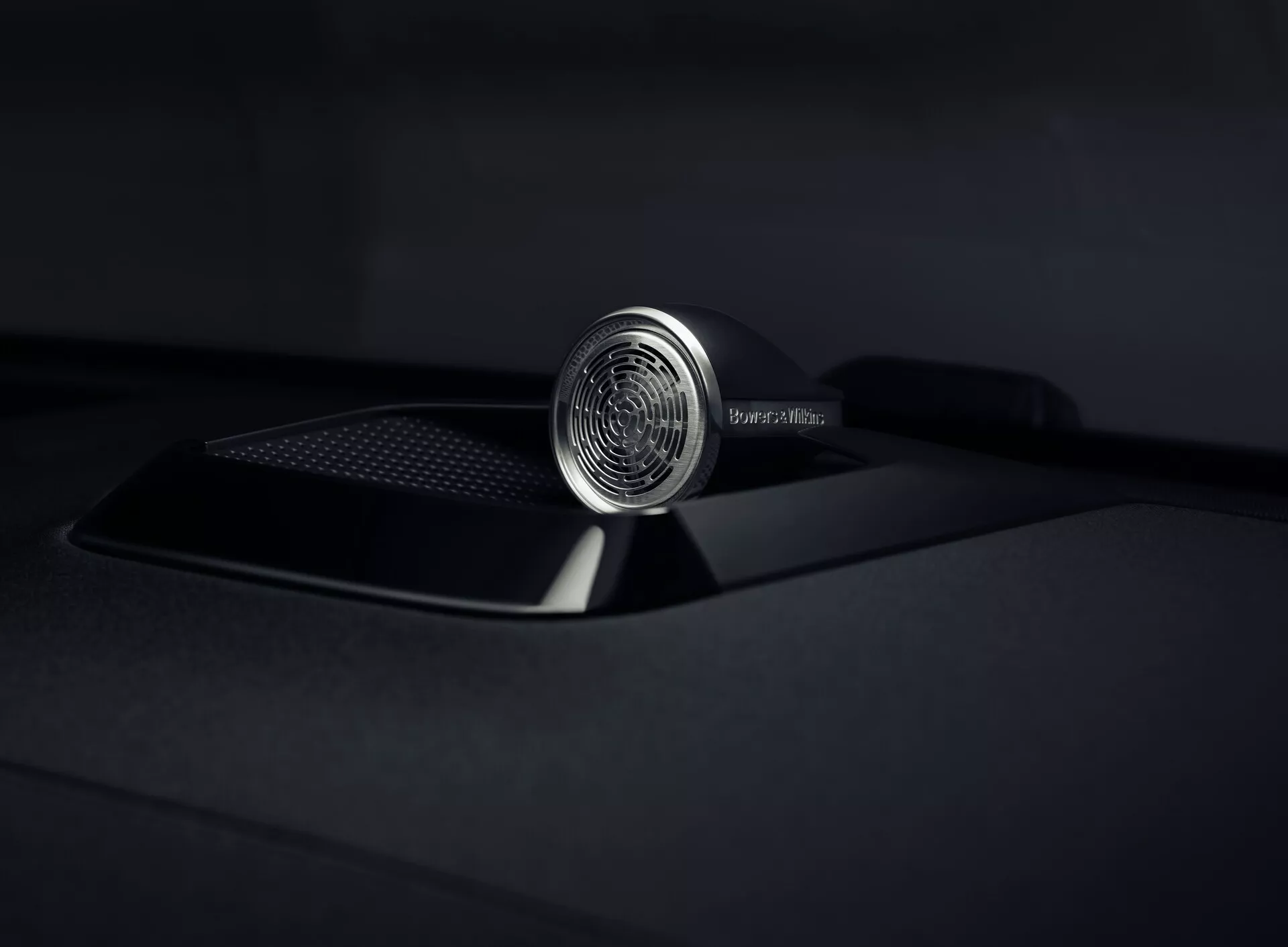 Zbliżenie na ornament maski Polestar 3 2023 podkreślający jego skomplikowany projekt i luksusowe wykonanie, z detalnym okrągłym emblematem i elegancką matową czarną maską