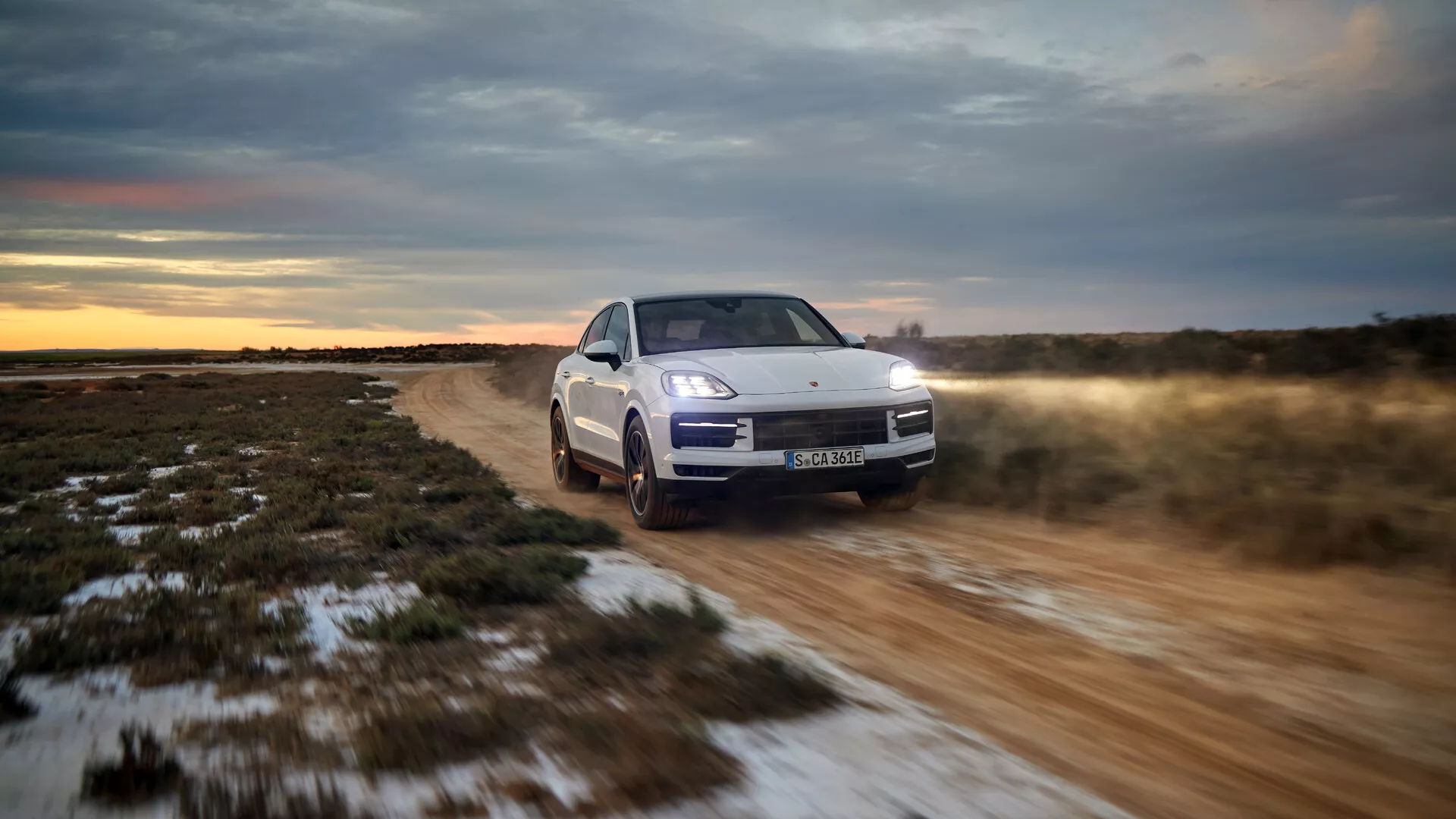 Model Porsche Cayenne 9YA Facelift z 2023 roku na off-roadzie, prezentujący widok z przodu pod kątem trzech kwart z reflektorami LED, aktywnym zawieszeniem i systemem napędu na wszystkie koła o zmierzchu