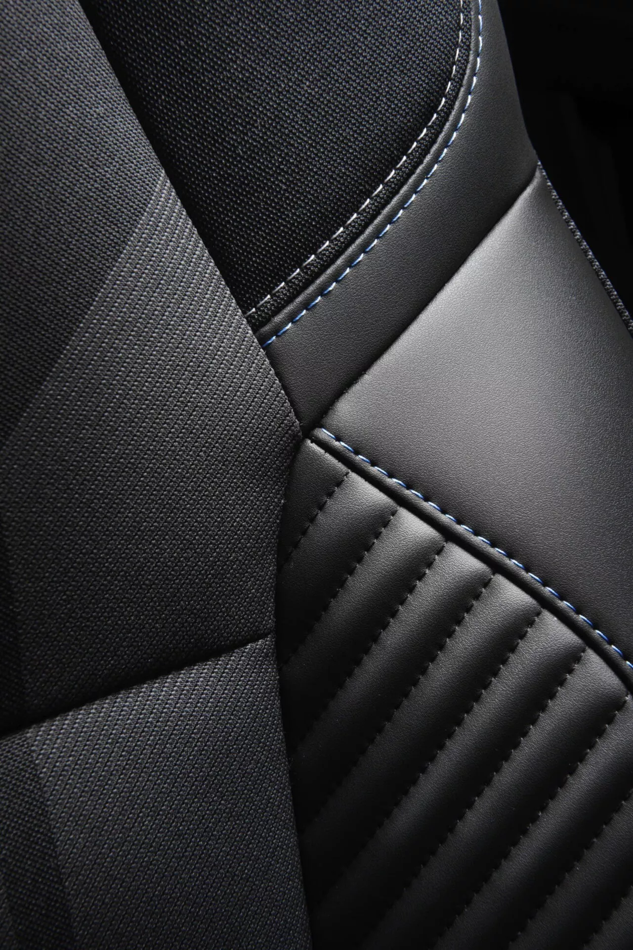 Szczegółowe zbliżenie na fotel Renault Captur 2024 (II-Facelift) skupiające się na teksturach tapicerki i rzemiośle szycia, z kontrastującymi materiałami