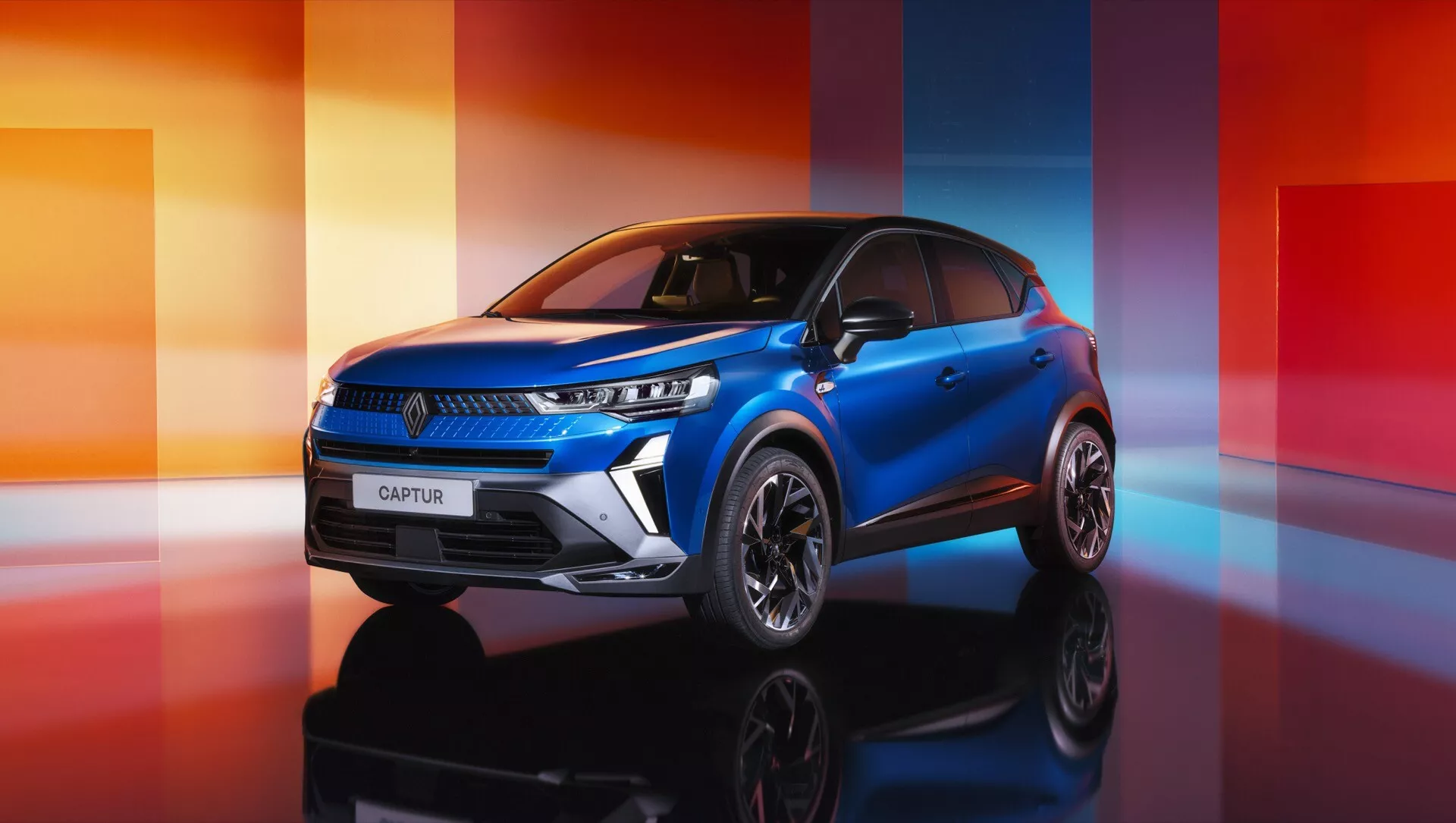 Renault Captur II lifting 2024 uchwycony z kąta trzech czwartych z przodu, prezentujący jego eleganckie reflektory LED, stylowe felgi aluminiowe i wysokiej jakości niebieski lakier w scenerii studia