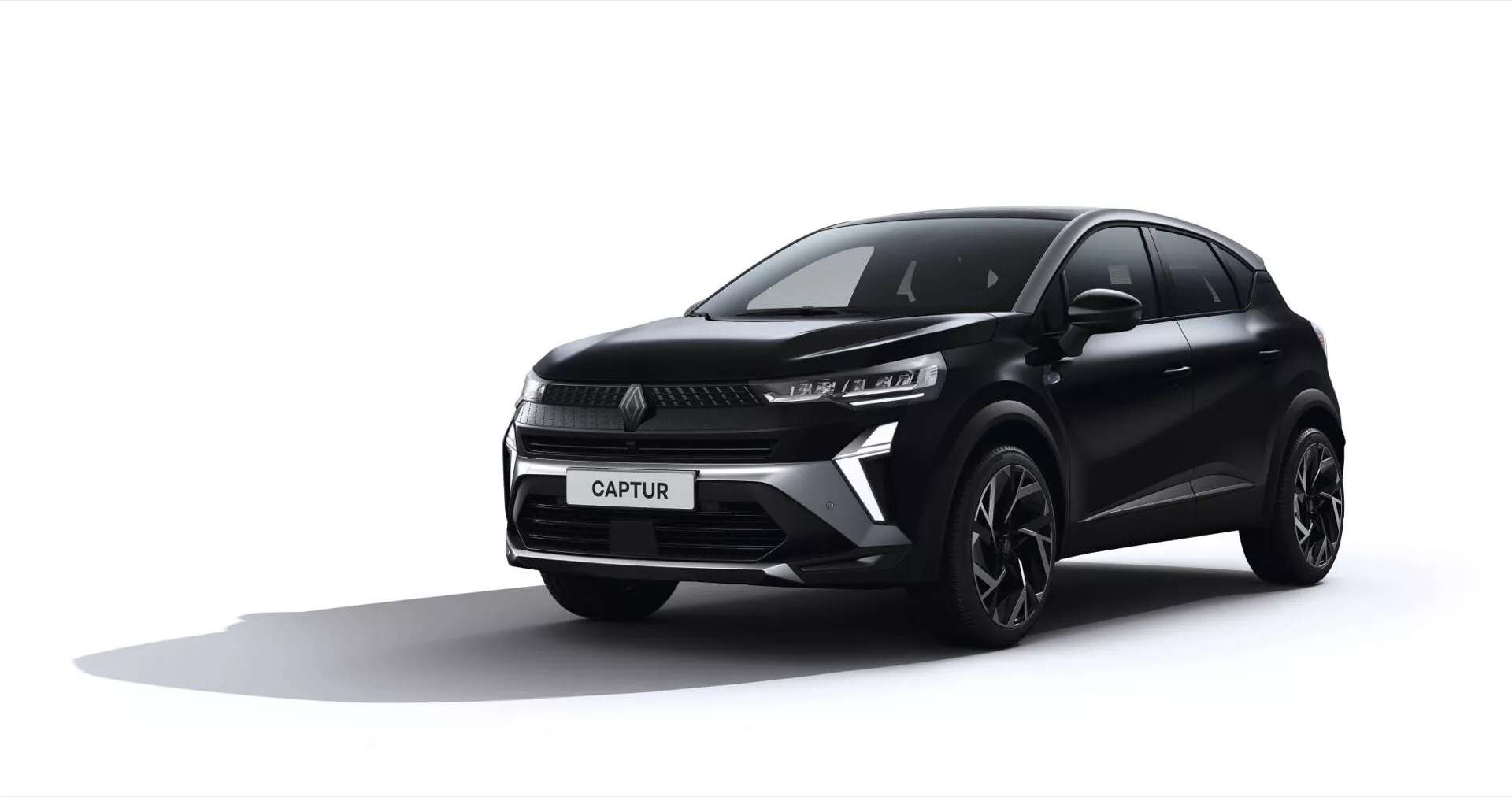 Trzy czwarte widoku przedniego czarnego Renault Captur 2024, pokazującego smukłe reflektory LED, wyróżniającą się kratkę z centralnym logiem, sportowy zderzak z wlotami powietrza, felgi aluminiowe oraz aerodynamiczne kształty