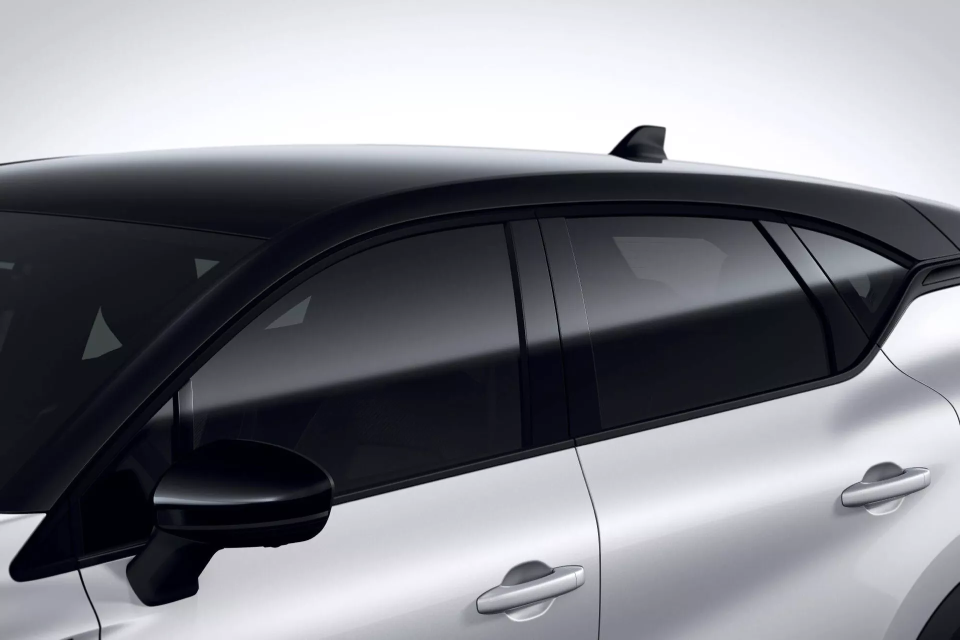 Zbliżony boczny widok Renault Captur 2024 (II-facelift) podkreślający jego aerodynamiczną linię dachu, wyszukaną antenę w kształcie płetwy rekina i nowoczesny design okien z czarnym, bezramkowym szkłem otoczonym czarnymi słupkami B, ustawiony na eleganckim, sportowym profilu z klamkami drzwi dopasowanymi kolorystycznie, sugerujący zaawansowaną technologię wejścia bezkluczykowego