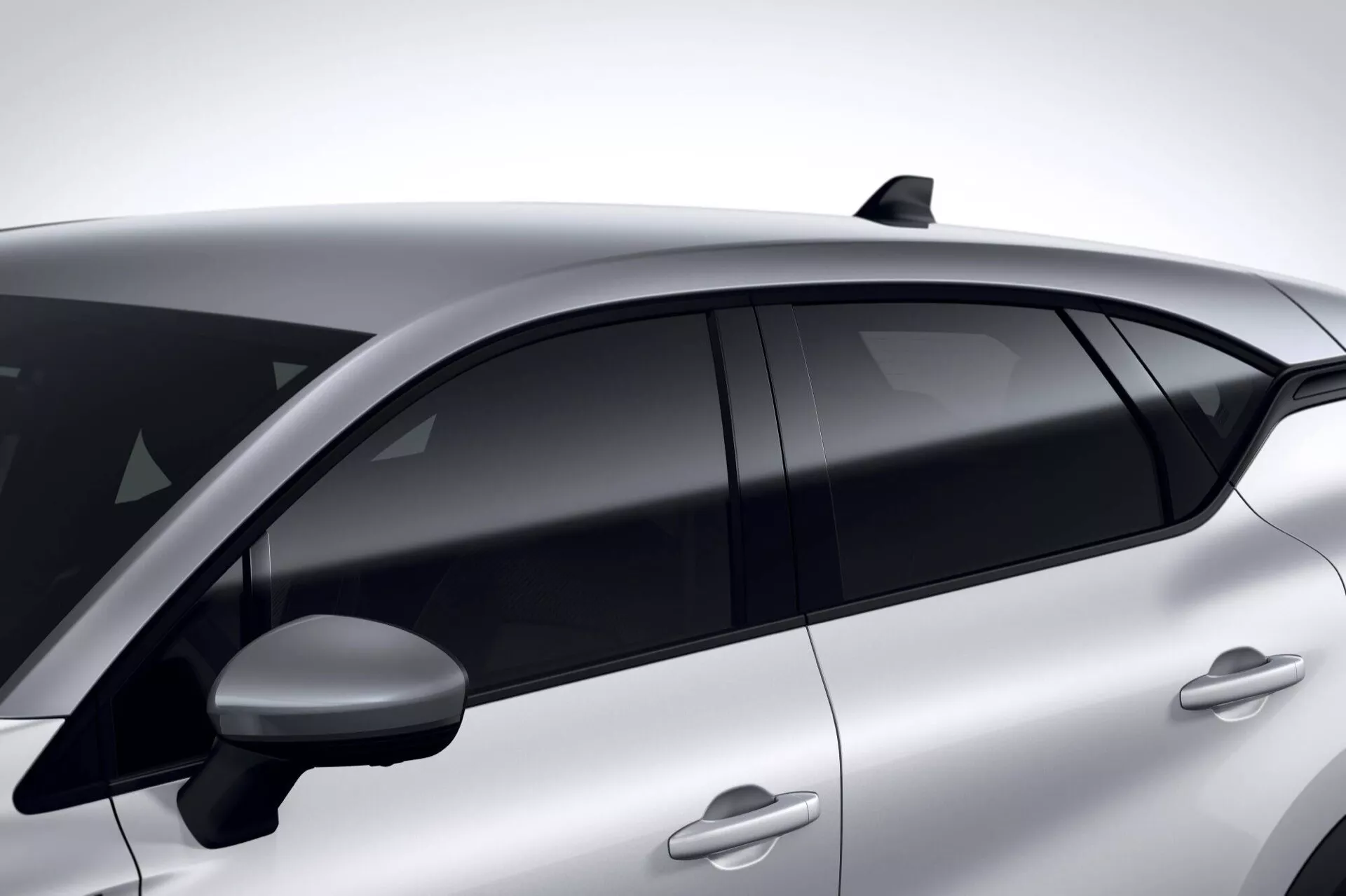 Renault Captur II lifting 2024 z metalicznym wykończeniem, przedstawiający eleganckie klamki drzwi w kolorze karoserii, przyciemniane szyby dla prywatności, zintegrowaną antenę dachową dla zaawansowanej łączności i aerodynamiczne lusterko boczne, uchwycone w trzech czwartych bocznego widoku podkreślające jego nowoczesne elementy projektu.