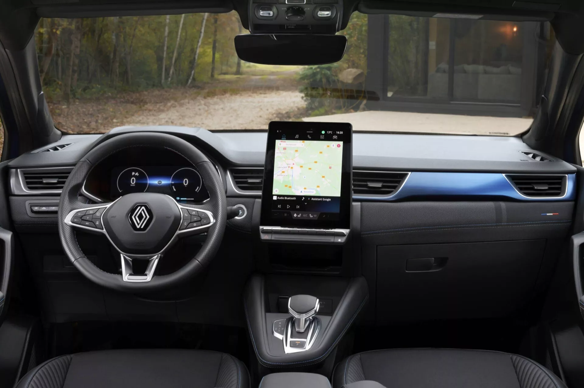 Widok wewnętrzny Renault Captur 2024 z tylnego siedzenia, podkreślający cyfrowy kokpit, wielofunkcyjną kierownicę, duży system infotainment z ekranem dotykowym i minimalistyczny design konsoli środkowej