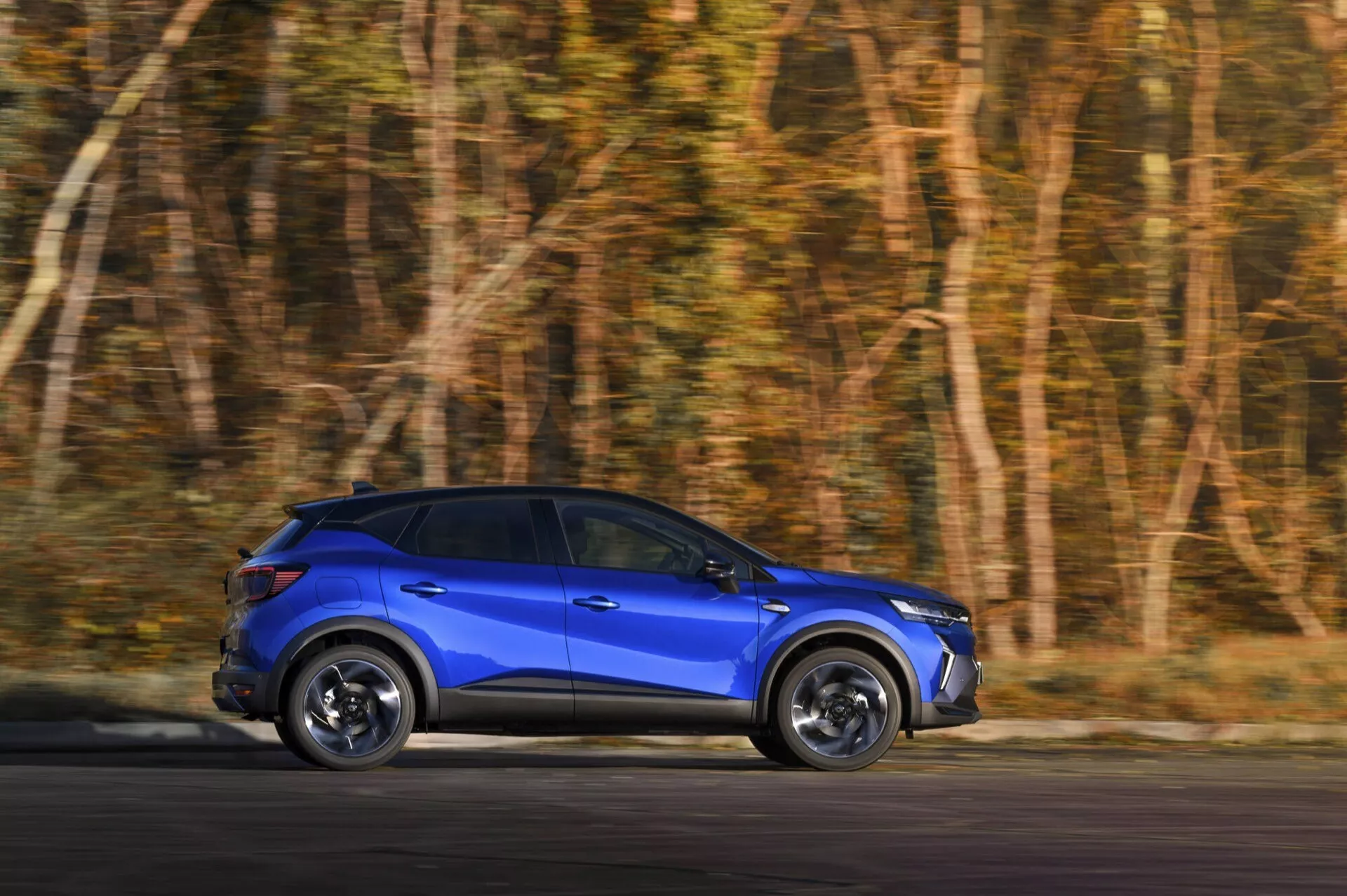 Niebieski SUV Renault Captur II Facelift 2024 w ruchu, prezentujący dynamiczne cechy projektu i technologię LED z bocznego profilu z widocznym rozmyciem ruchu