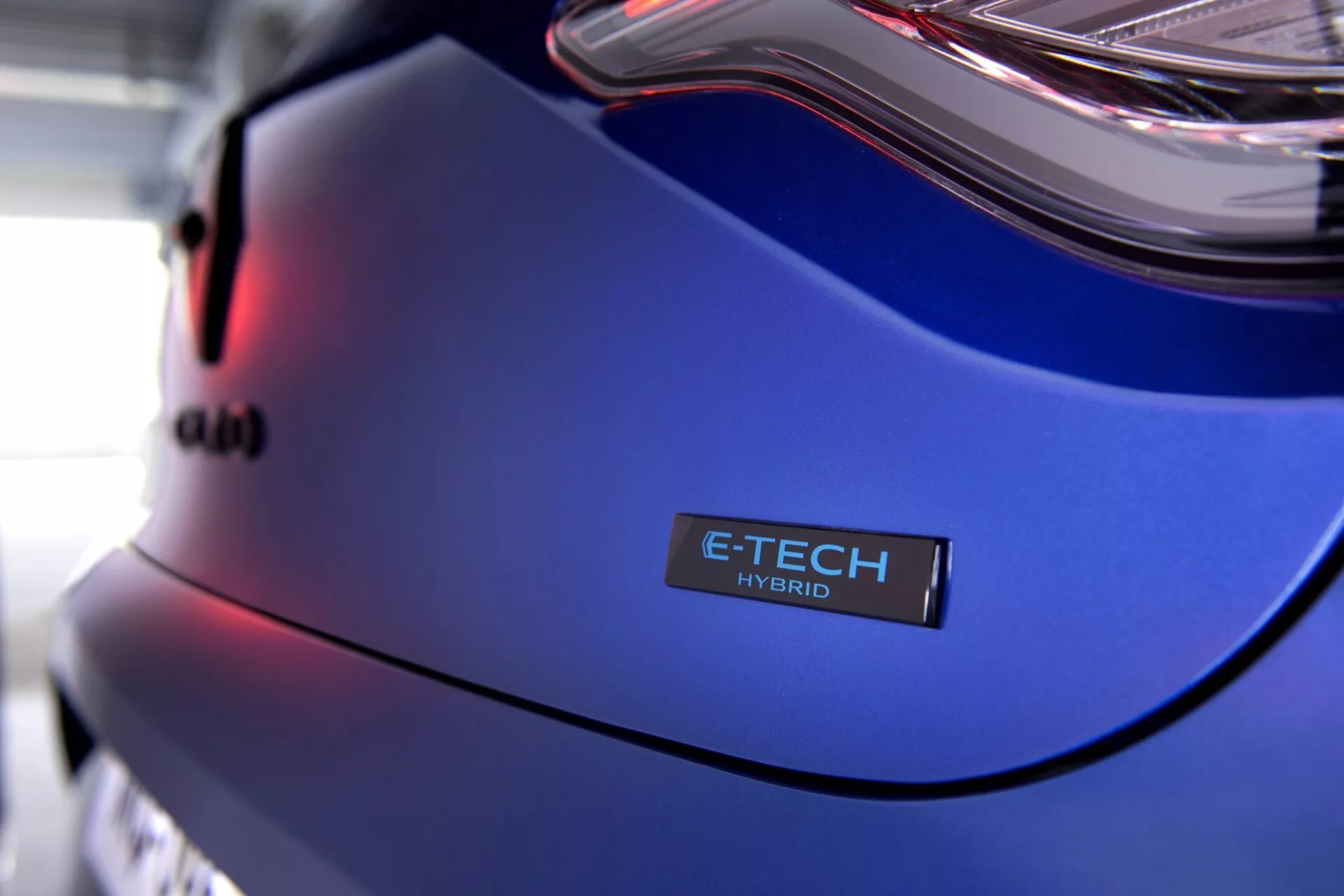 Zbliżenie na Renault Clio V-Facelift 2023 z panelu tylnego, odznaką E-TECH HYBRID i metalicznie niebieskim lakierem