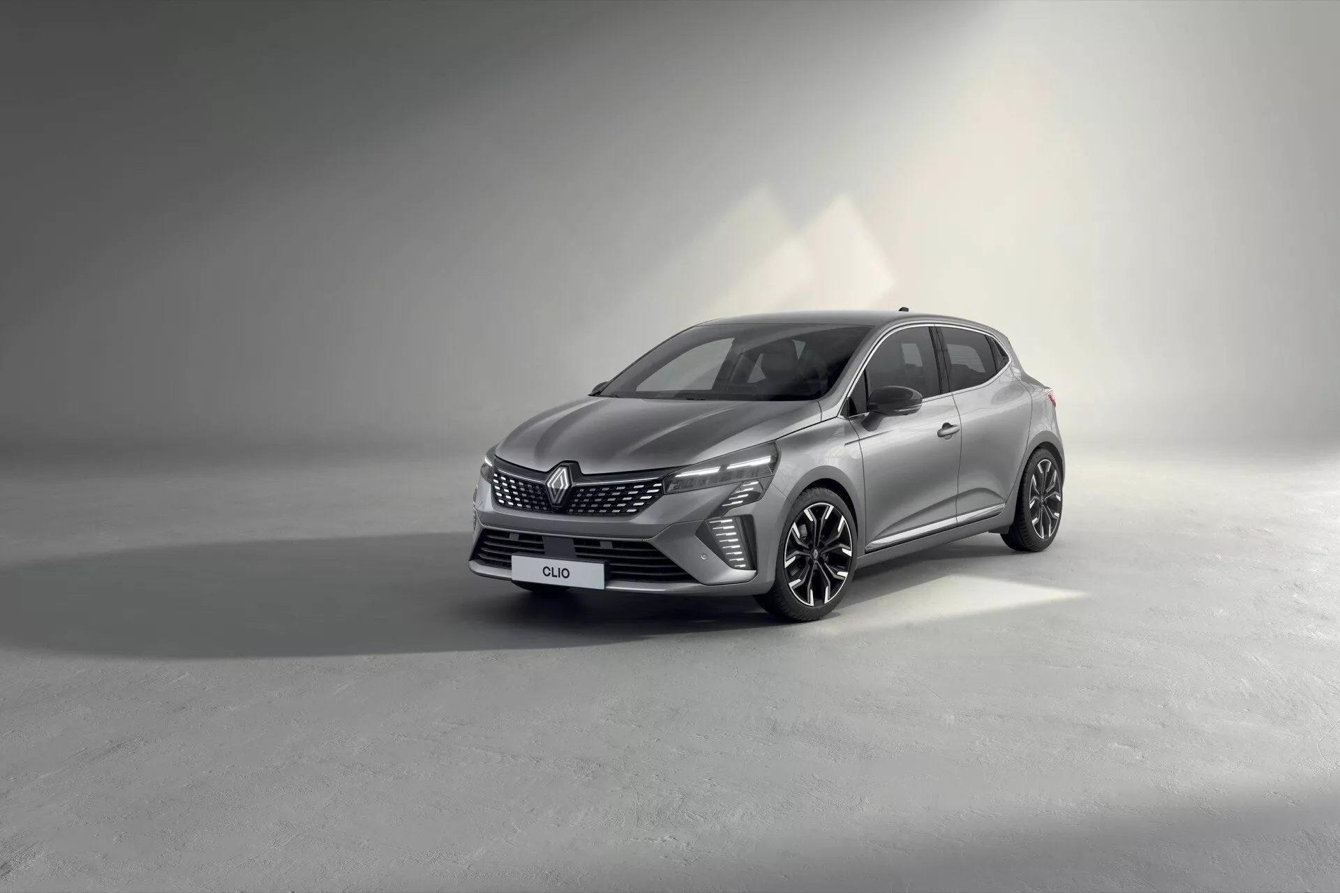 Model Renault Clio V-facelift 2023 zaprezentowany w studio, pokazujący jego nowoczesny design i funkcje z perspektywy trzy czwarte z przodu, podkreślający grill pojazdu, reflektory LED, wieloramienne koła ze stopu i wyszukaną karoserię z kontrolowanym oświetleniem, aby podkreślić szczegóły.