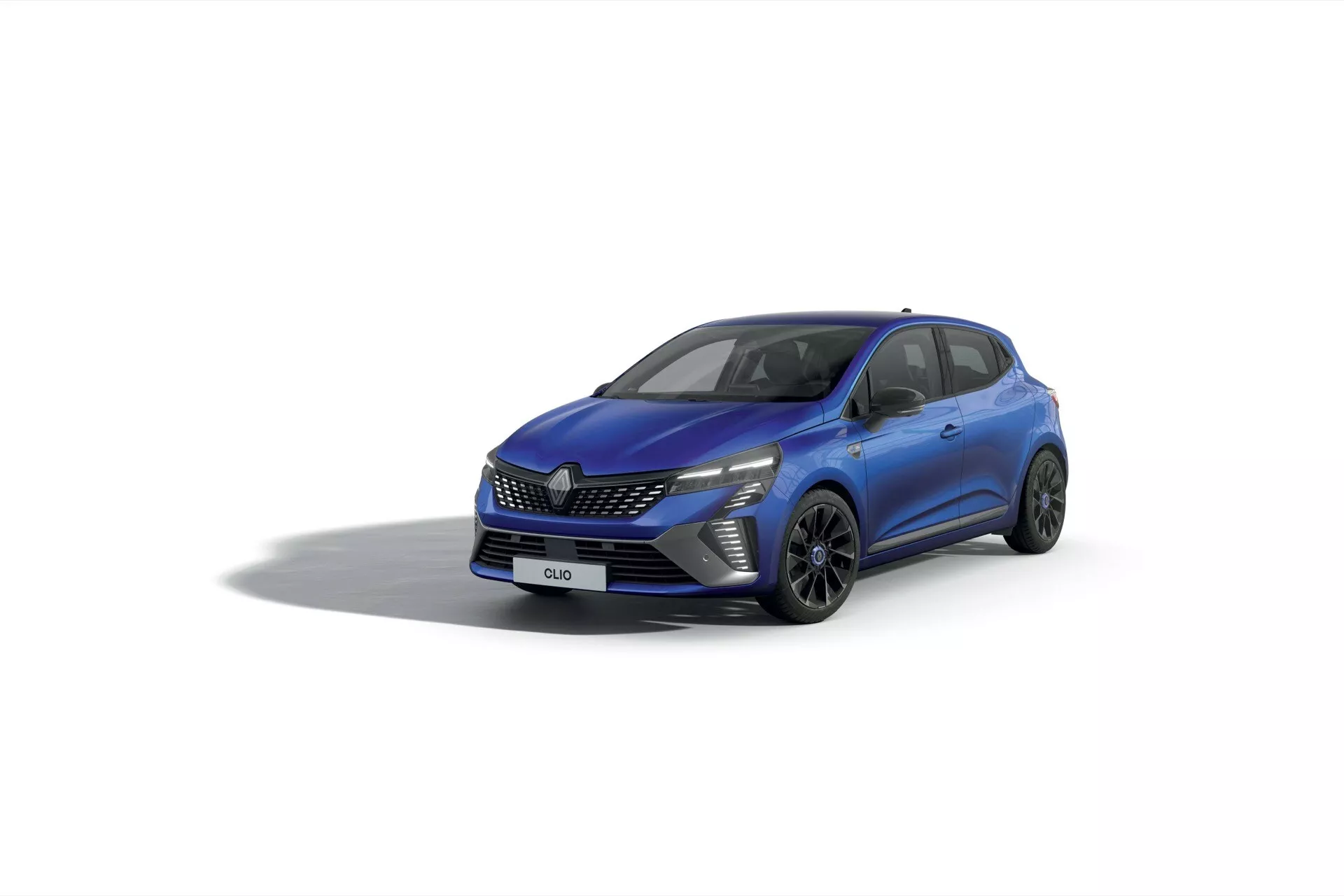 Renault Clio V-Facelift 2023 z widoku trzy czwarte od przodu przedstawiające reflektory LED, wzorzystą atrapę chłodnicy, alufelgi o wielu ramionach i dynamiczne linie nadwozia na jasnym tle studia