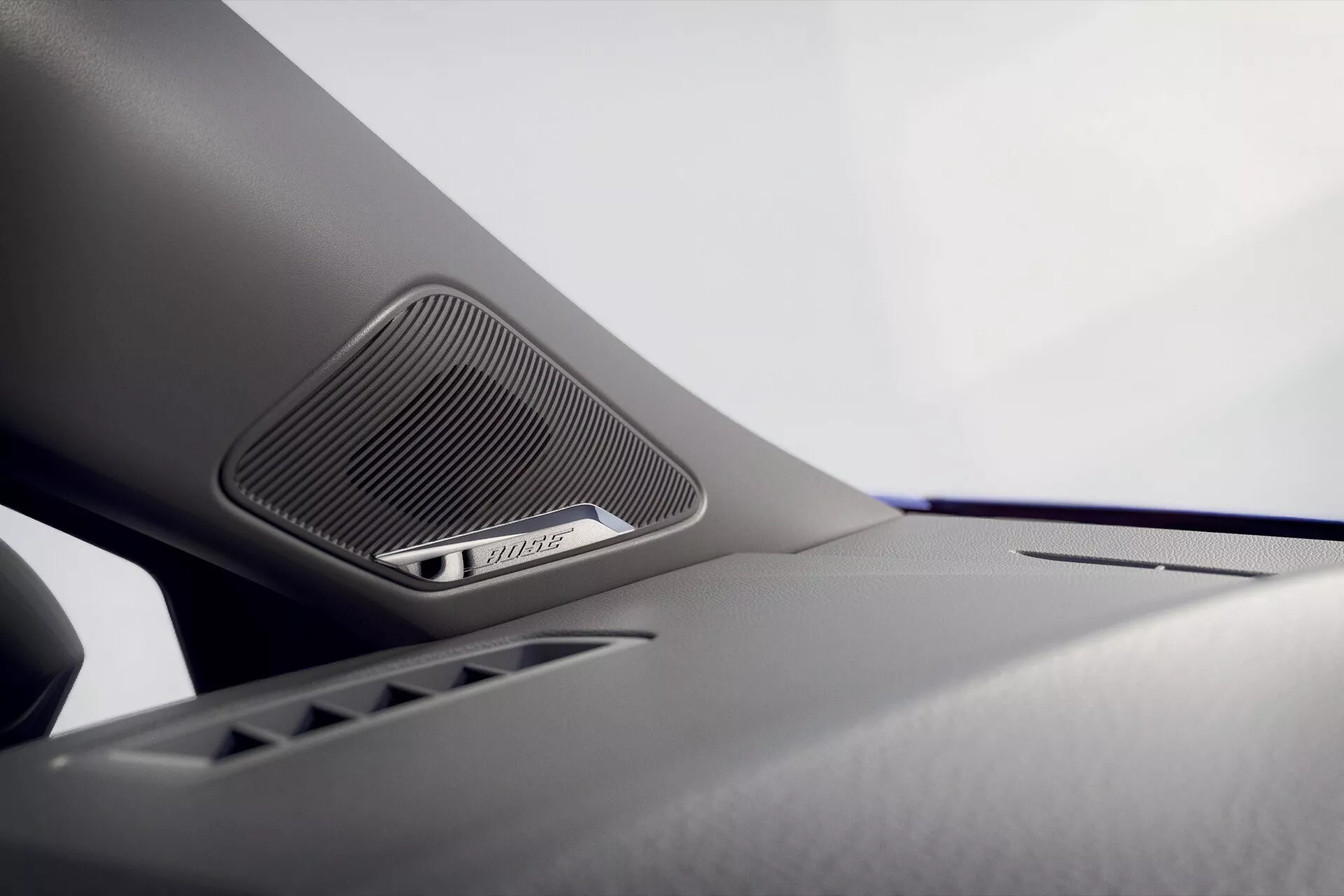 Zbliżenie na zintegrowany system głośnikowy w Renault Clio 2023 v-facelift, z trójkątną kratką sugerującą wysokiej jakości dźwięk, przeciw tłu detali projektowych wnętrza pojazdu