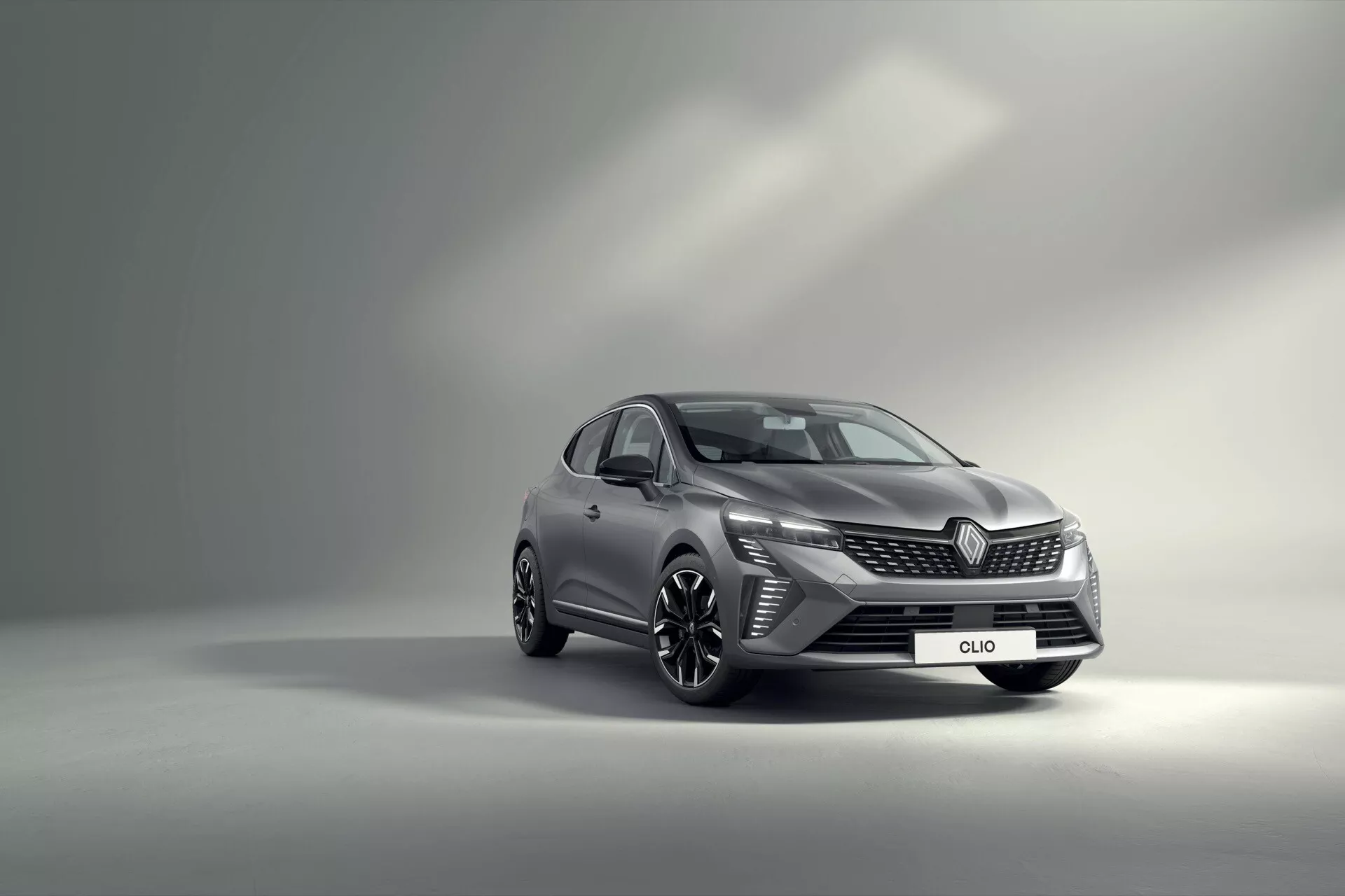 Renault Clio V-facelift 2023 prezentujące swój dynamiczny design z widokiem z przodu z trzech czwartych na tle gradientu studia, podkreślające reflektory LED, wyrafinowaną przednią kratę, sportowe felgi aluminiowe i zintegrowane wskaźniki w lusterkach bocznych.