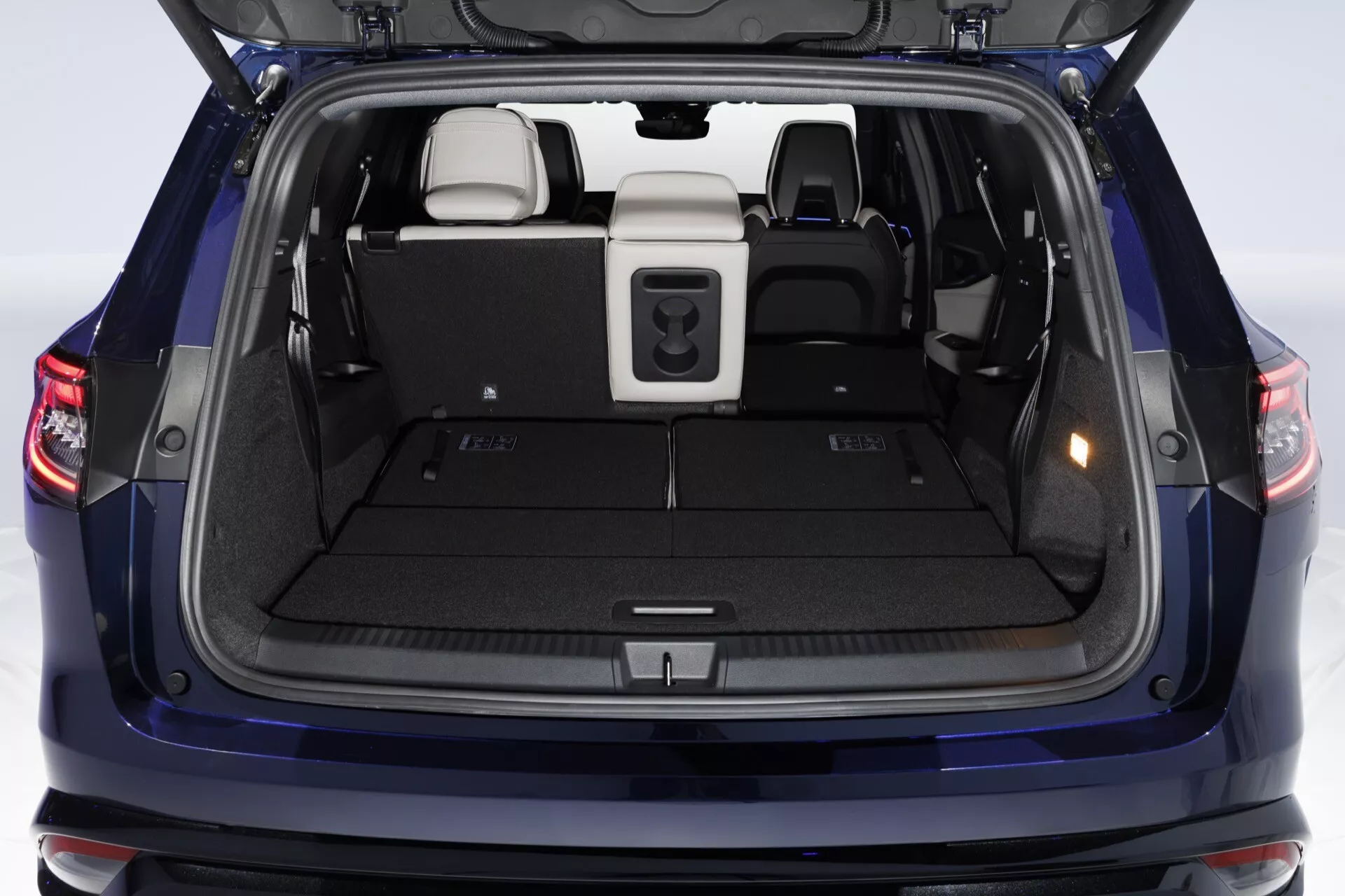 Tylna przestrzeń bagażowa Renault Espace 2023 z otwartą klapą bagażnika, tylnymi siedzeniami dzielonymi w proporcji 60/40, chowaną osłoną bagażu, ergonomicznymi uchwytami do zamykania i dywanikiem w neutralnych tonacjach