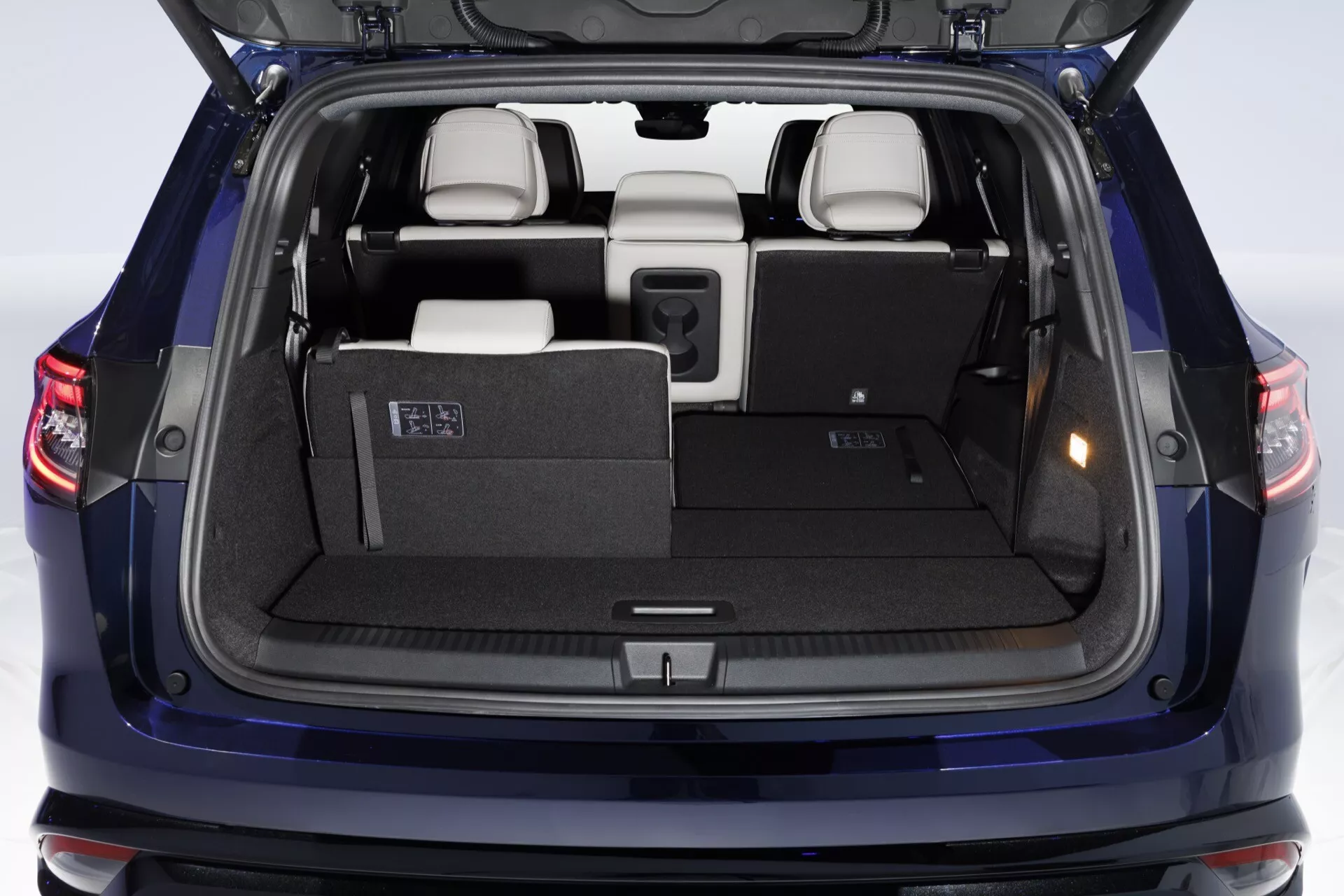 Renault Espace VI 2023 pokazujący widok z tyłu z otwartą klapą bagażnika, podkreślający przestronny bagażnik, tylne światła LED, składane siedzenia trzeciego rzędu, materiały wysokiej jakości we wnętrzu, łatwe w obsłudze dźwignie konfiguracji siedzeń, pokrowiec prywatności, szczegółowe wykończenie klapy bagażnika oraz czujniki parkowania