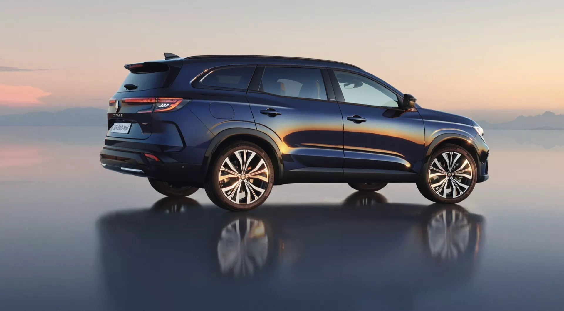 Średniokątny boczny profil Renault Espace VI 2023, prezentujący luksusowy design SUV z relingami dachowymi, tylnymi światłami LED, spojlerem tylnym, podwójnym wydechem i aluminiowymi kołami o kilku ramionach, skupiony na użyteczności i przygodzie, ustawiony przeciwko cyfrowo renderowanemu horyzontowi odbijającym się na gładkiej powierzchni.
