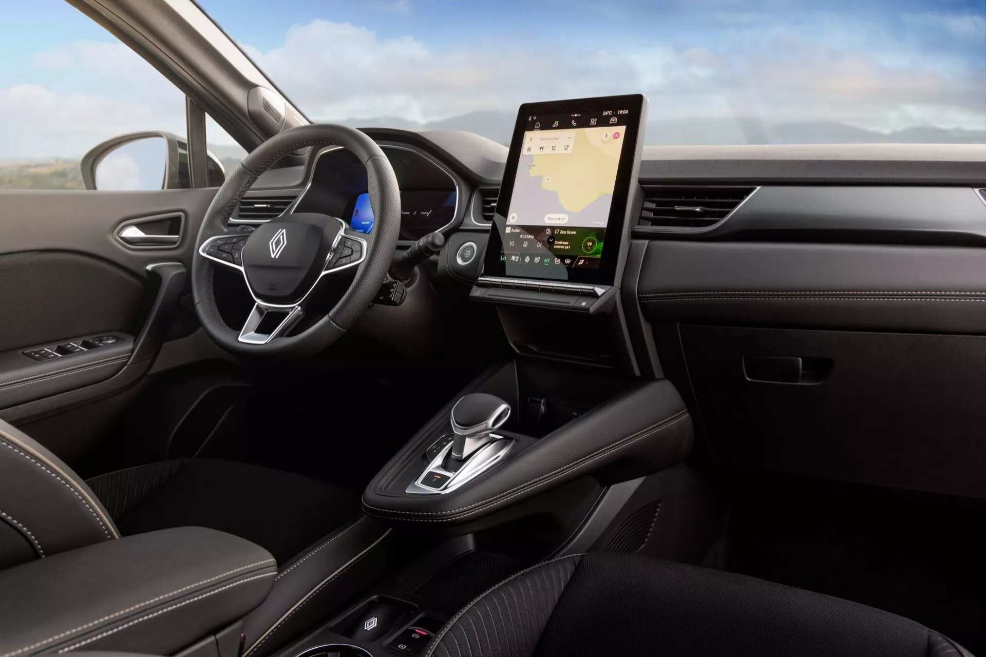 Wnętrze Renault Symbioz 2024 pierwszej generacji z perspektywy kierowcy, skupiające się na desce rozdzielczej, kierownicy i pionowo zorientowanym ekranie infotainmentu. Kierownica ma zamontowane kontrolki do obsługi audio i komend głosowych, z częściowo widocznym cyfrowym zestawem wskaźników za nią. Elegancka i minimalistyczna deska rozdzielcza integruje zaawansowane opcje łączności, takie jak nawigacja i integracja ze smartfonem, podczas gdy konsola centralna zawiera elektroniczny selektor biegów, uchwyty na kubki i dodatkowe kontrolki. Ciemne skórzane tapicerki z kontrastującymi szwami, akcenty drewniane i metalowe wykończenia sugerują luksusowy i technologicznie zaawansowany pojazd, prawdopodobnie wyposażony w systemy wspomagania kierowcy.