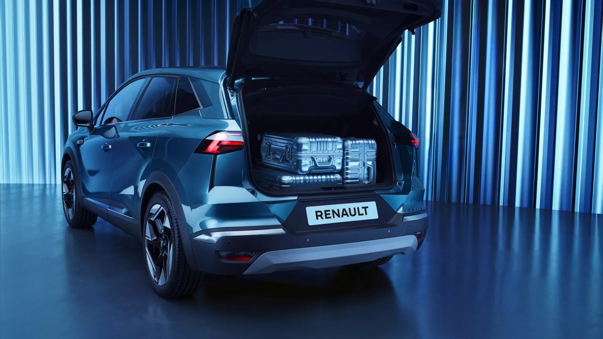 Widok tylnej części Renault Symbioz 2024 pierwszej generacji w kolorze ciemnoniebieskim, ukazujący przestronny otwarty bagażnik, charakterystyczne tylne światła LED, chromowany napis 'RENAULT' na pokrywie bagażnika, nowoczesny design tylnej szyby, wieloramienne felgi aluminiowe i studyjne otoczenie z futurystycznym błękitnym tłem.