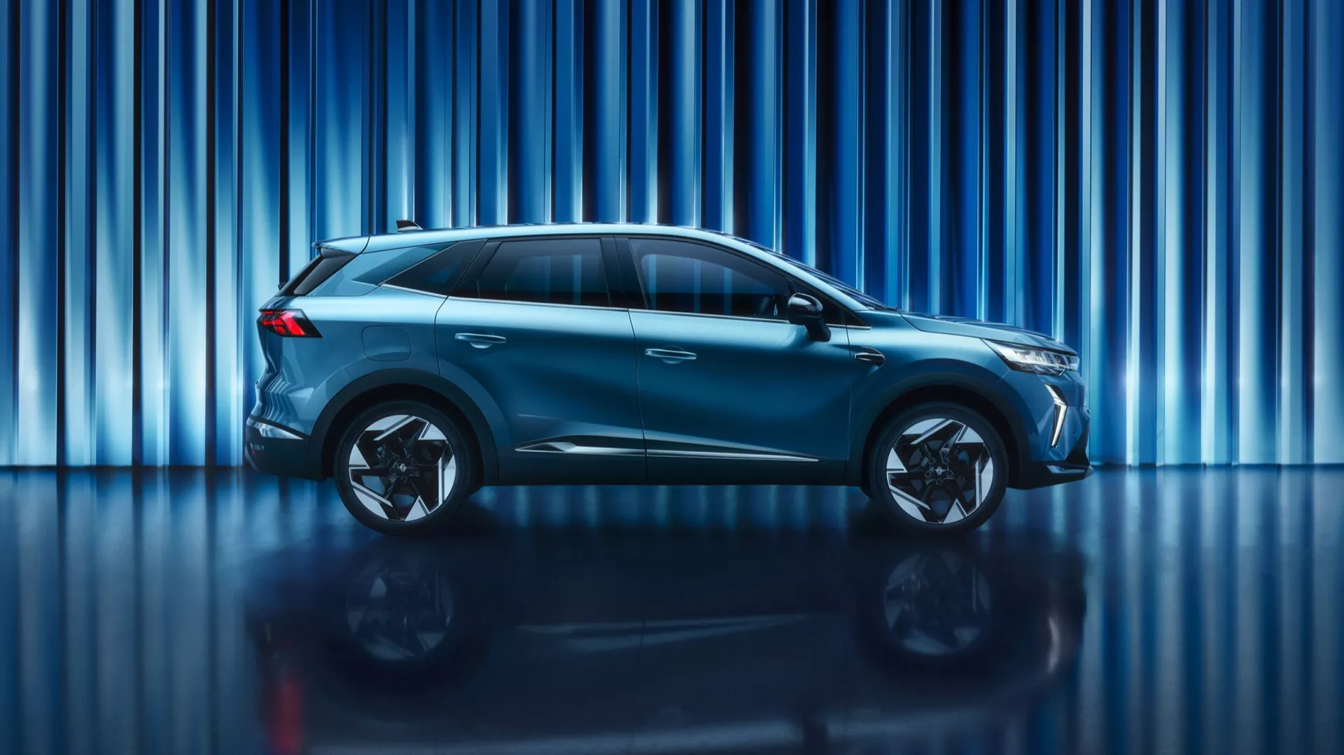 Widok boczny Renaulta Symbioz z 2024 roku przedstawiający jego elegancki, aerodynamiczny design, wieloramienne felgi aluminiowe, podniesiony prześwit i zintegrowane lusterka boczne, podkreślający nowoczesny SUV/crossover w środowisku studyjnym.