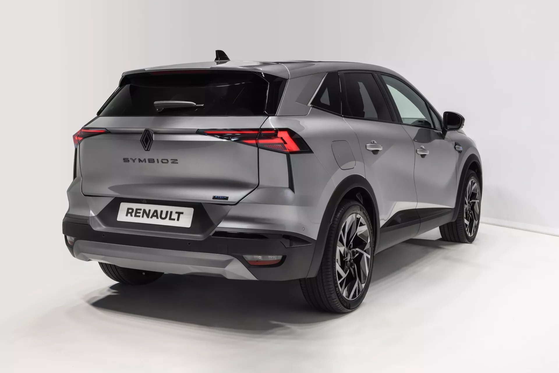 Obraz przedstawia nowoczesne SUV widziane z perspektywy trzech czwartych tyłu, podkreślające rzeźbiony profil tylny i boczny. Charakterystyczne cechy to poziomo rozciągnięte tylne światła LED, pochylona tylna szyba z zintegrowanym spojlerem, czujniki i kamera w tylnym zderzaku dla bezpieczeństwa oraz aluminiowe koła z wieloramiennym wzorem. Pojazd jest pomalowany na metaliczny kolor, który podkreśla jego krzywizny i kanciasty design. Brandy i odznaki są wyraźnie widoczne na tylnej klapie, wskazując na różne nowoczesne udogodnienia, takie jak bezkluczykowy dostęp, tylne czujniki parkowania i zaawansowane systemy oświetleniowe.