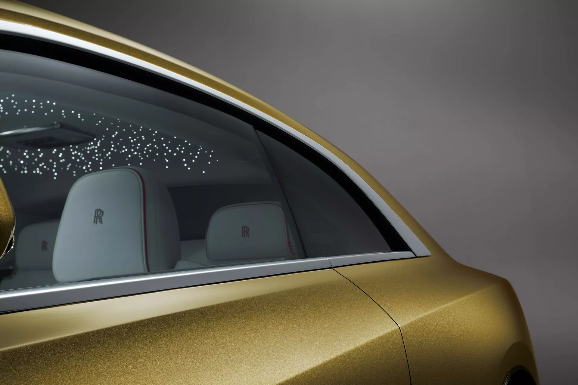 Szczegółowy widok boczny Rolls-Royce Spectre 2023, prezentujący metaliczne złote wykończenie, design okna tylnego, elegancką technologię drzwi oraz luksusowe detale marki