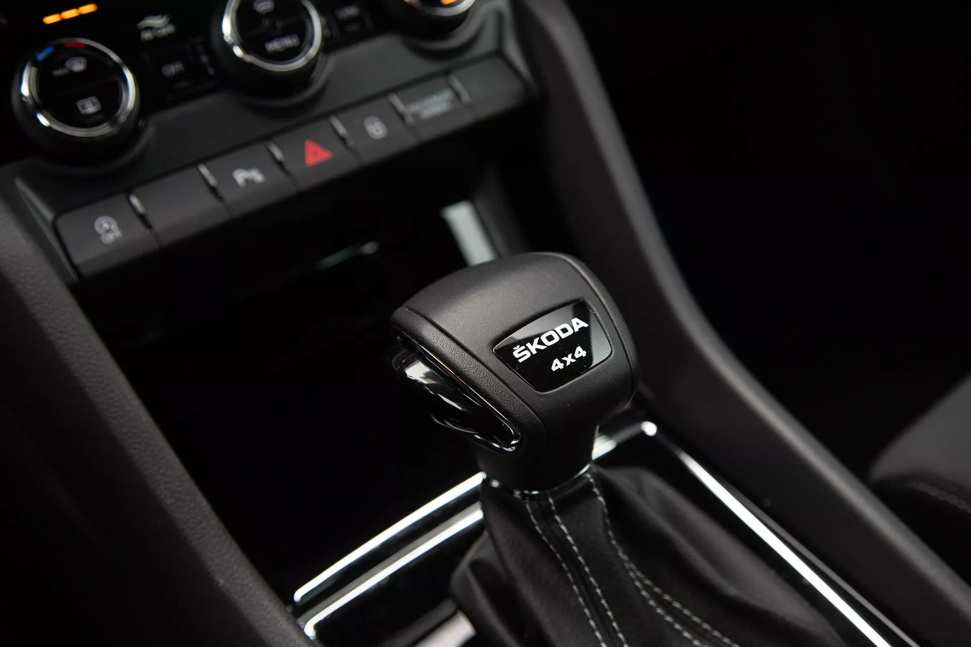 Automatyczna skrzynia biegów Škoda Karoq 2021 z napisem systemu 4x4 i logo Škoda, otoczona nowoczesnymi detalami wnętrza w błyszczącym czarnym i metalicznym wykończeniu.