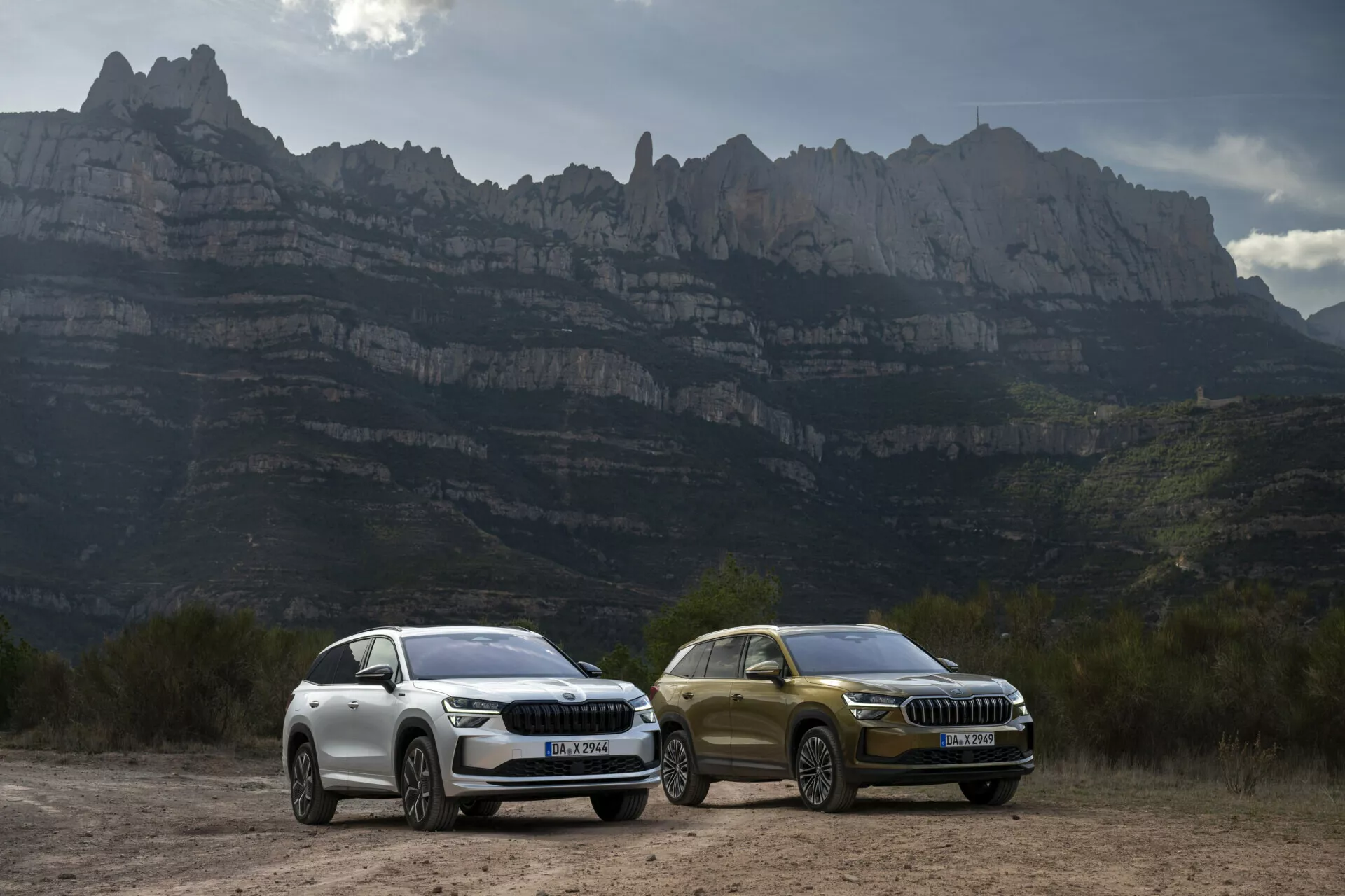 SUV-y Skoda Kodiaq 2024 z oświetleniem LED i luksusowymi detalami designu zaparkowane na zewnątrz na tle górskiego krajobrazu, podkreślające cechy aerodynamiczne, felgi aluminiowe i zaawansowaną technologię odpowiednią dla przygód na drodze.