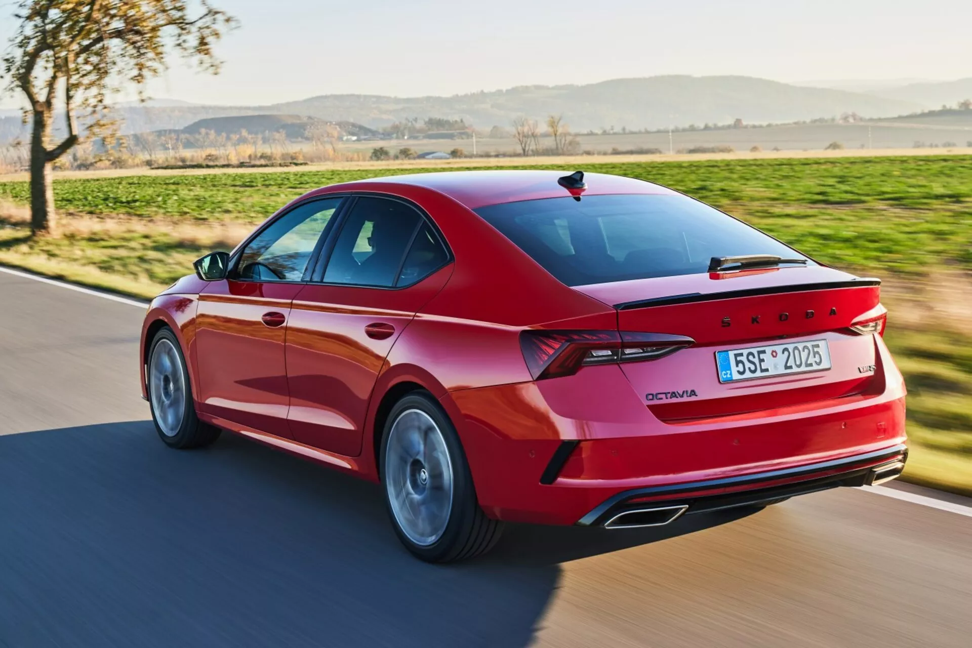 Dynamiczny widok z tyłu trzy czwarte limuzyny Skoda Octavia z 2017 roku w kolorze czerwonym, prezentujący sportowy zewnętrzny wygląd z LEDowymi światłami tylnymi, felgami ze stopów i zaawansowanymi funkcjami w naturalnym świetle dziennym
